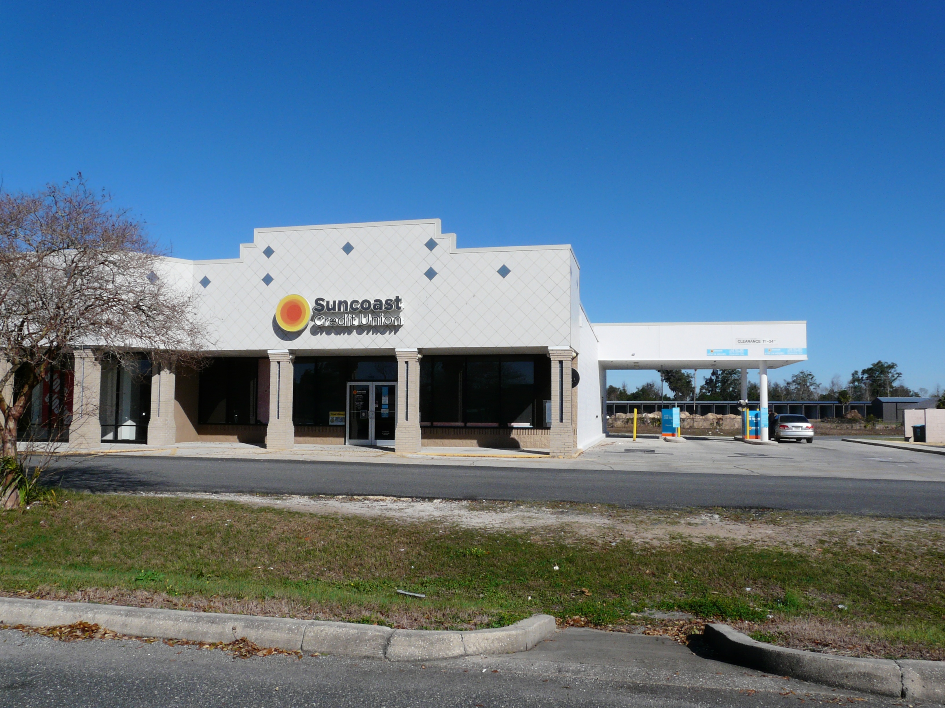 Suncoast Credit Union branch building with drive-through lane under a clear blue sky.