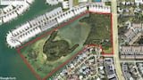 Satellite aerial view of a red-outlined waterfront parcel labeled Duhme Road Reserve along a bay.