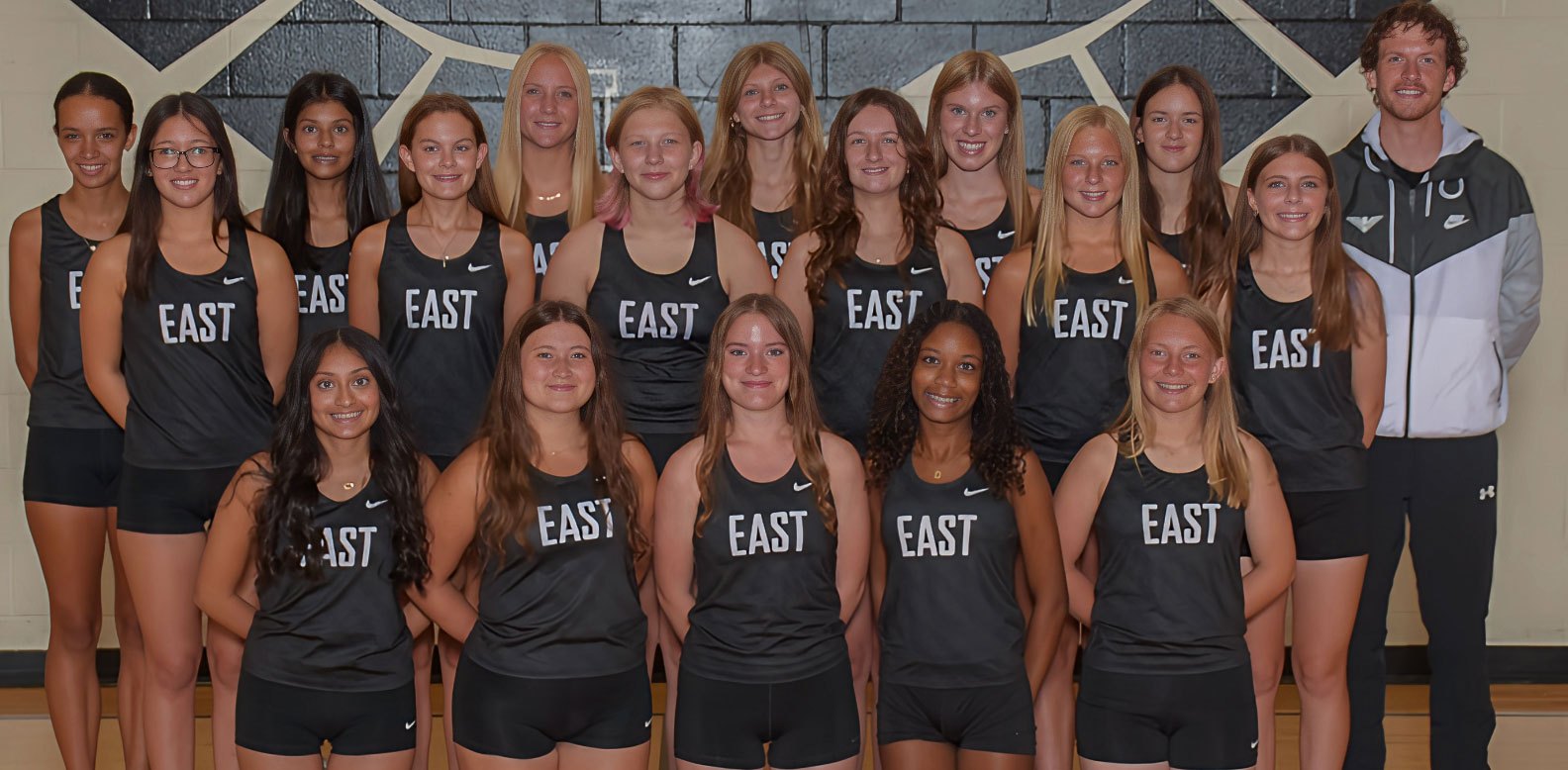 Group of young women in black 'EAST' athletic uniforms posed in two rows for a team photo.