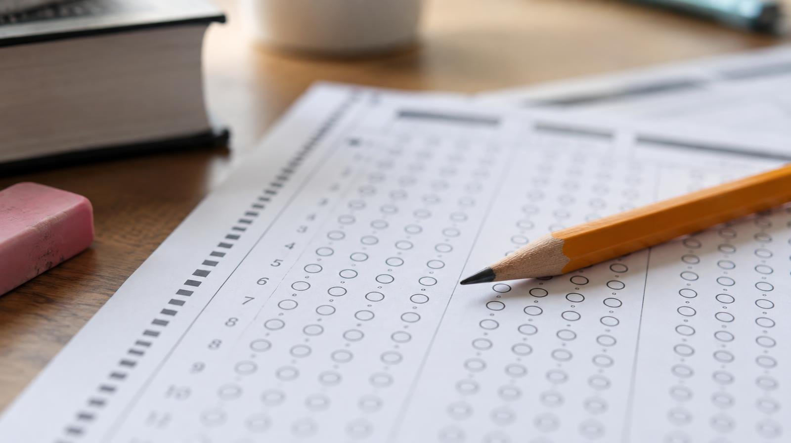 A sharpened pencil resting on a blank answer sheet with rows of empty bubbles.