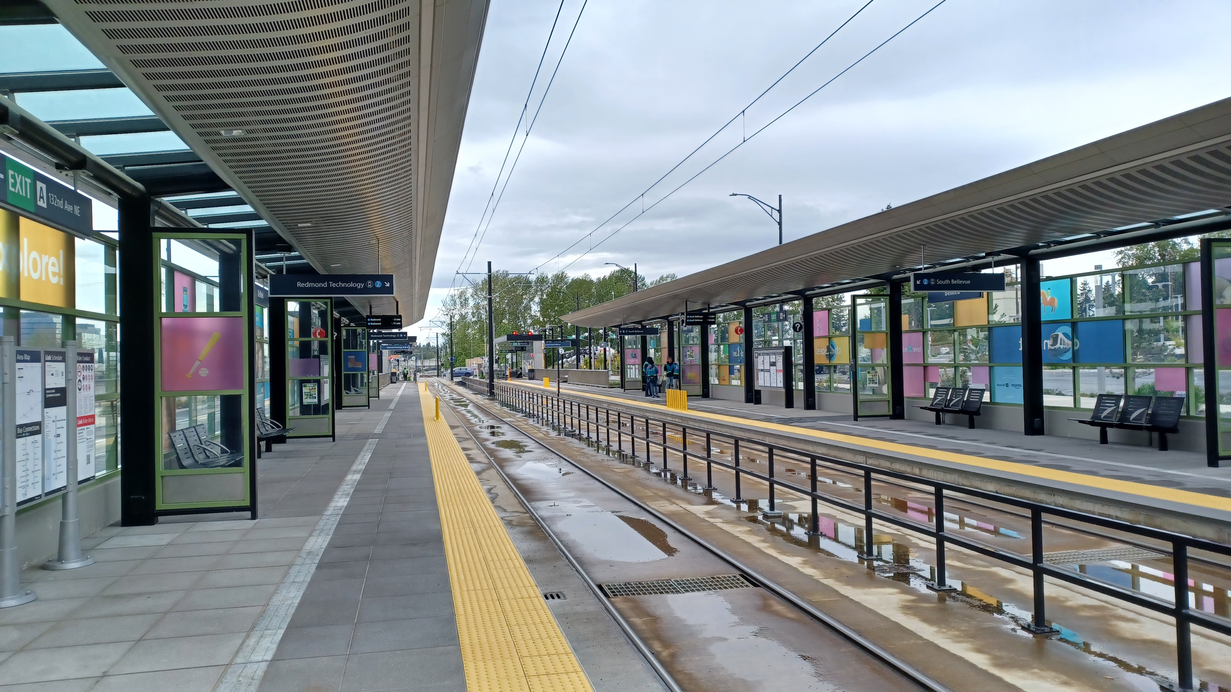 Empty light rail station platforms with curved metal canopies and yellow tactile safety strips.