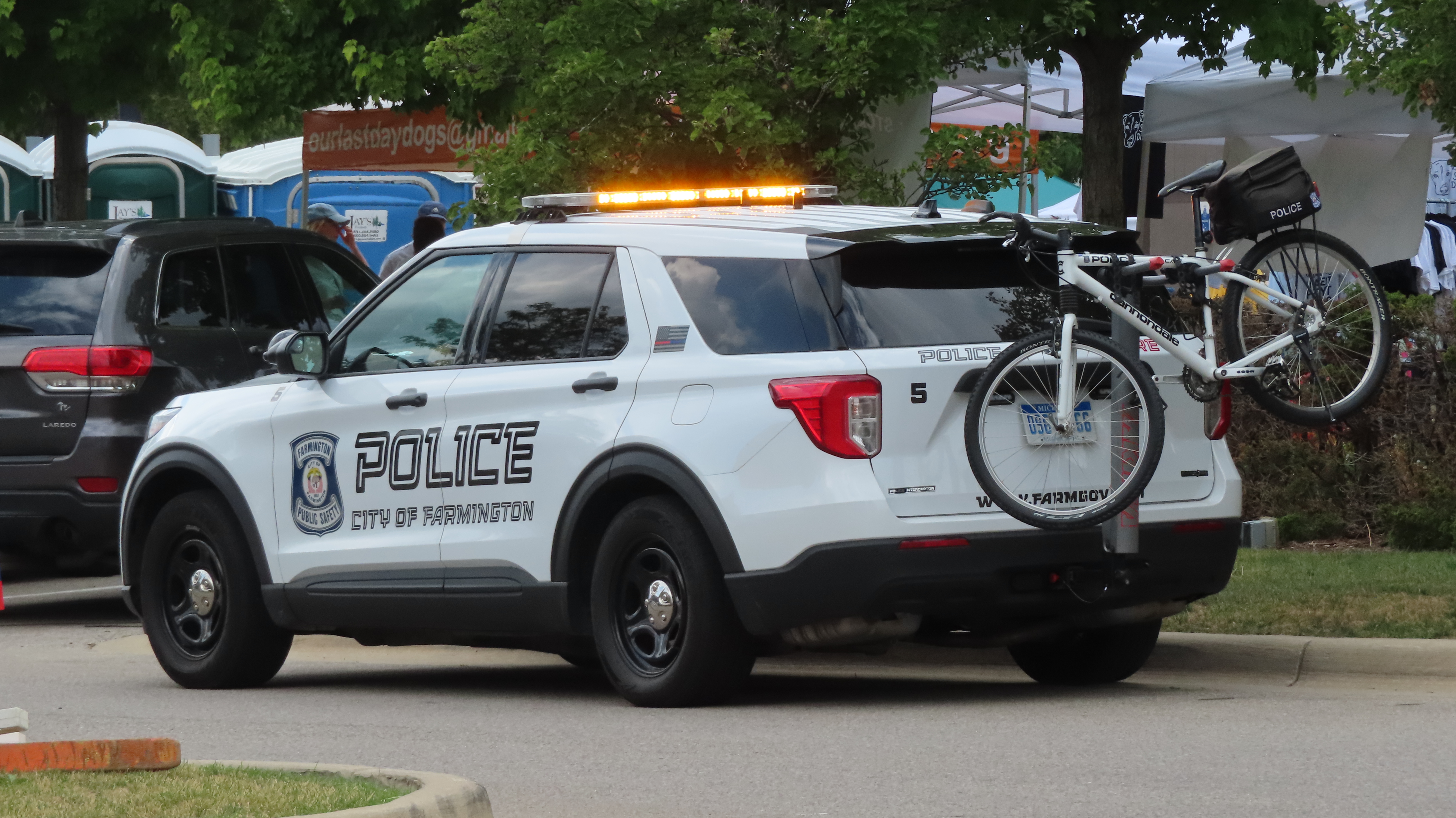 White City of Farmington police SUV with amber emergency lights on.