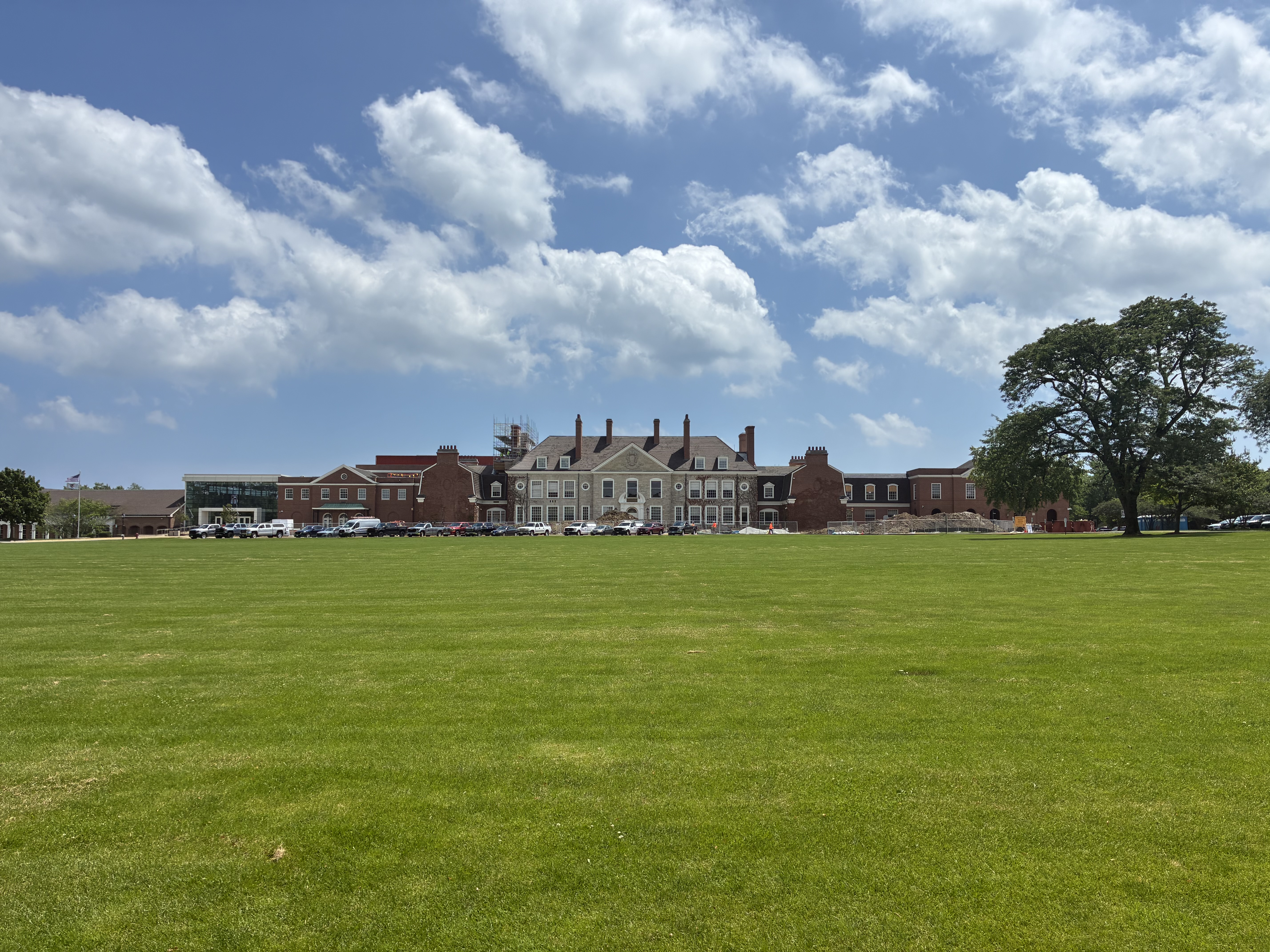 Large brick and stone high school building viewed across a wide green lawn.