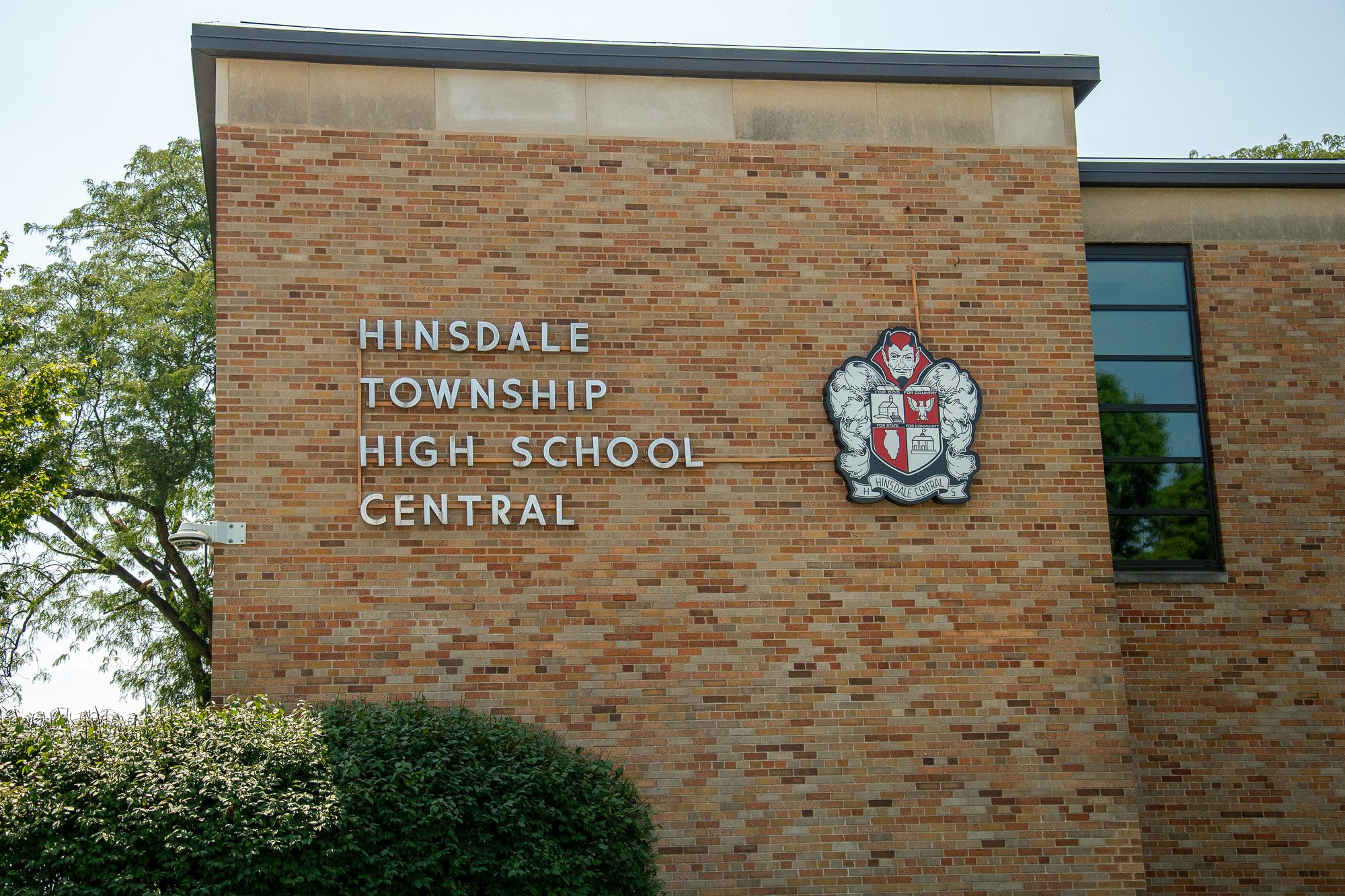 Brick exterior wall of a high school with name lettering and a red-and-white crest