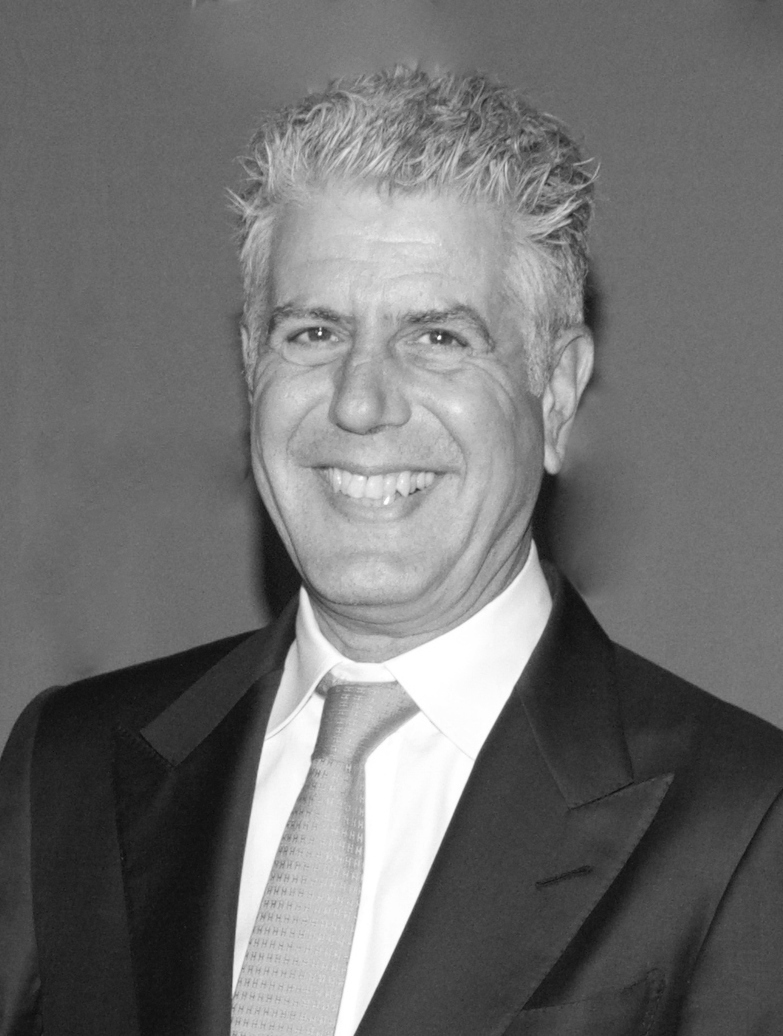 Black-and-white portrait of a smiling man in a dark suit jacket and tie.