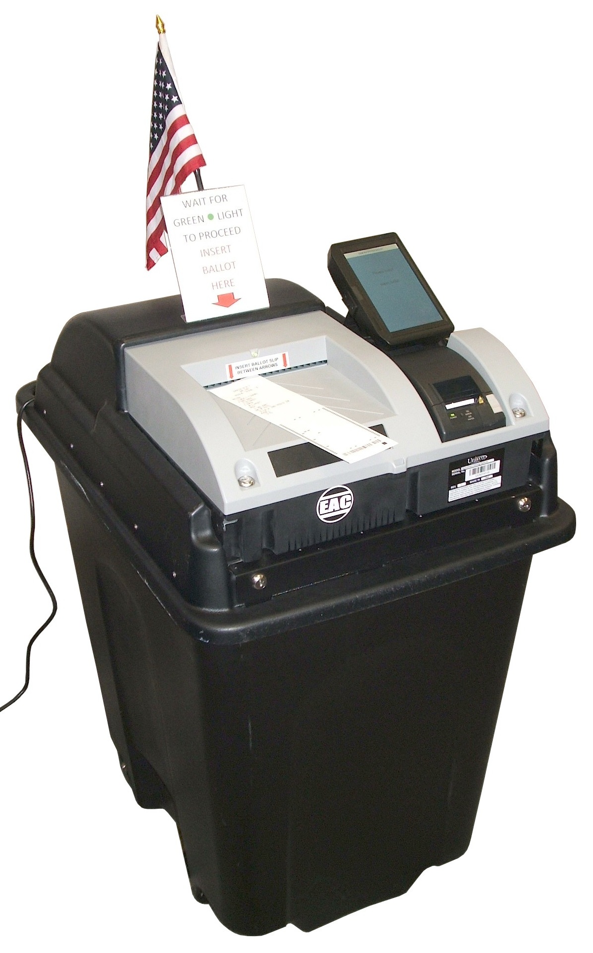 An optical scan ballot scanner mounted on a storage bin with a small American flag attached.