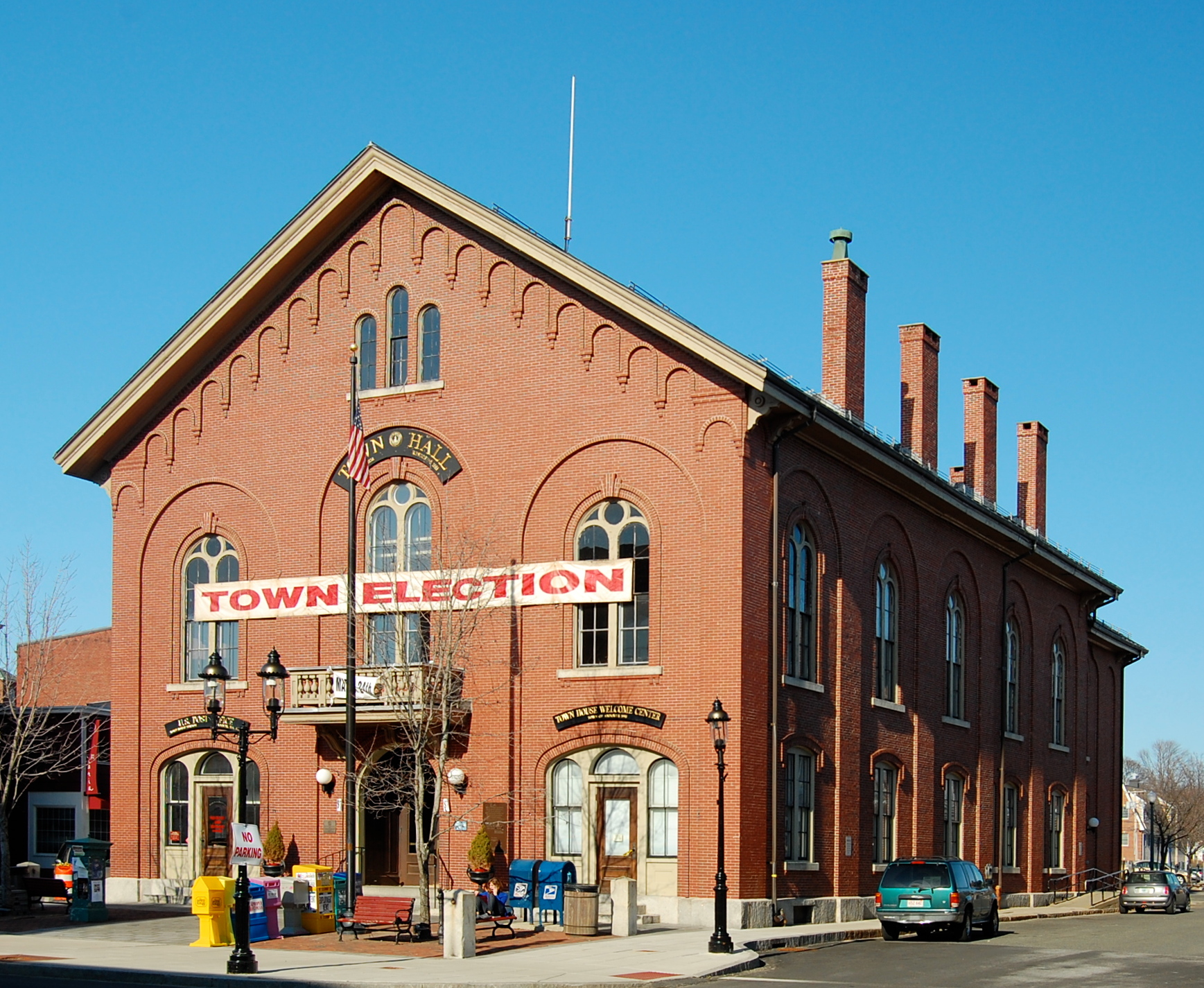 Red brick Victorian town hall building with arched windows and a banner on its facade.
