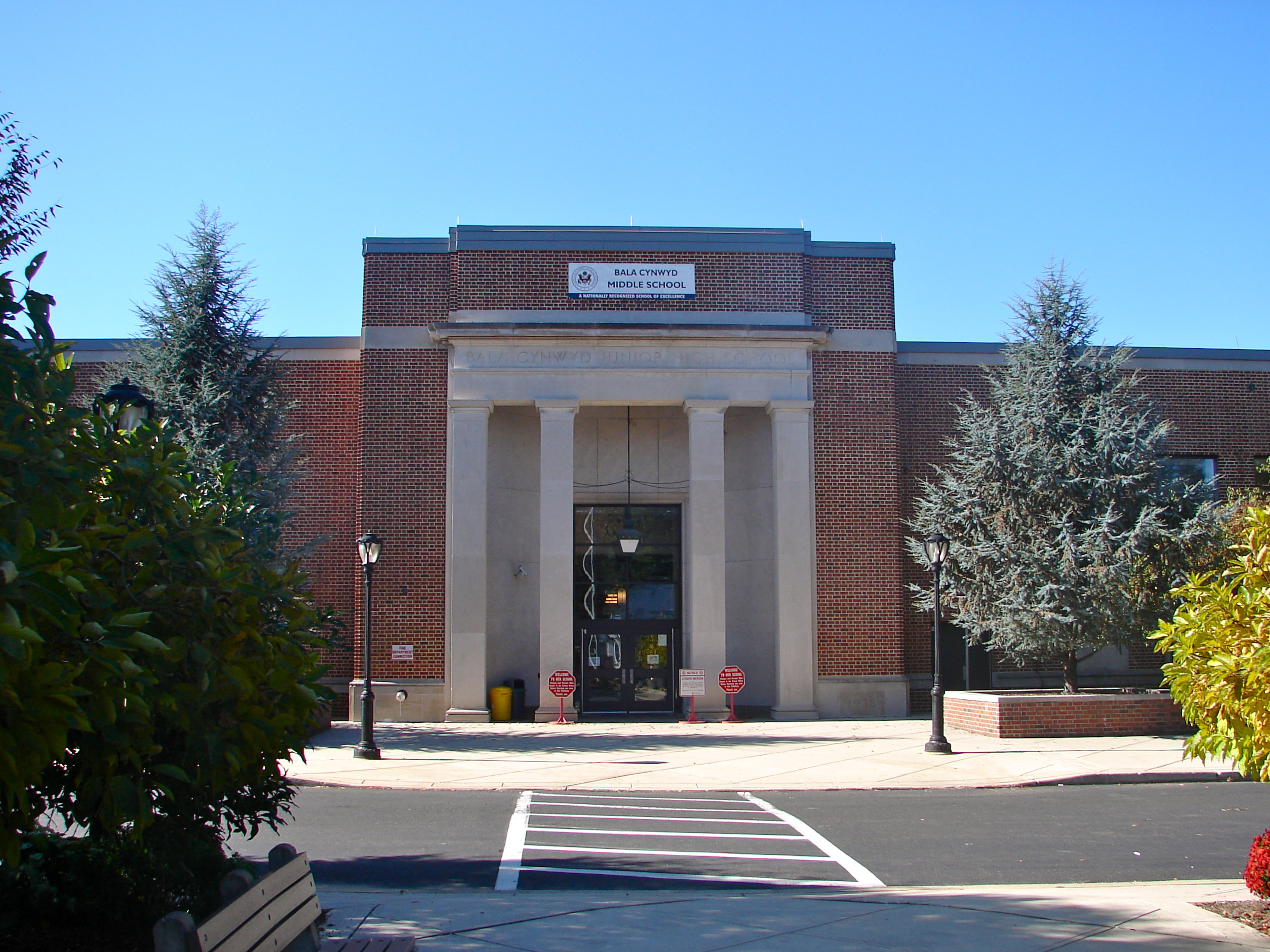 Brick school building with white columns and a formal entrance under a clear blue sky.