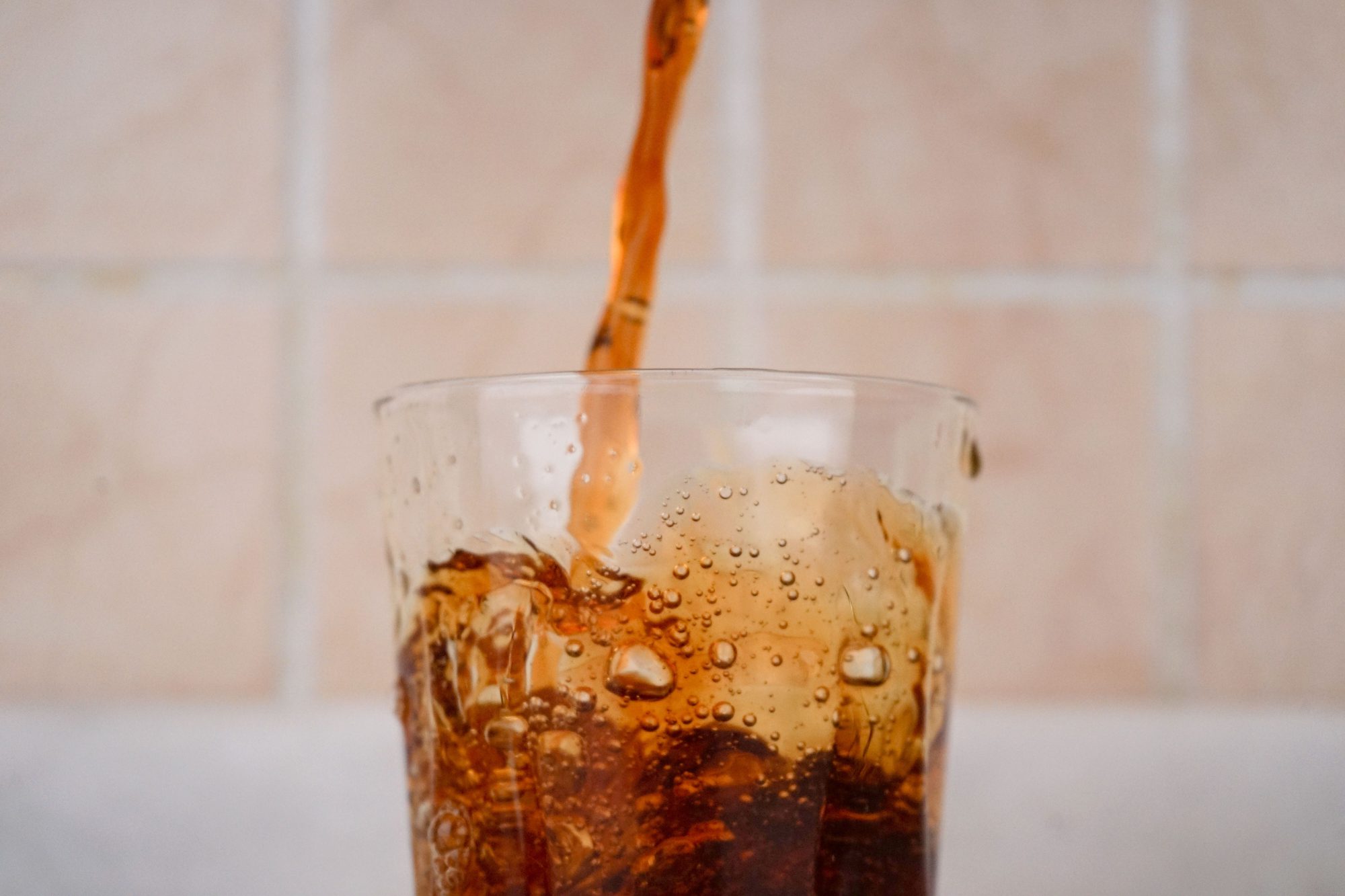 A close-up capture of soda being poured into a glass, creating a splash effect.
