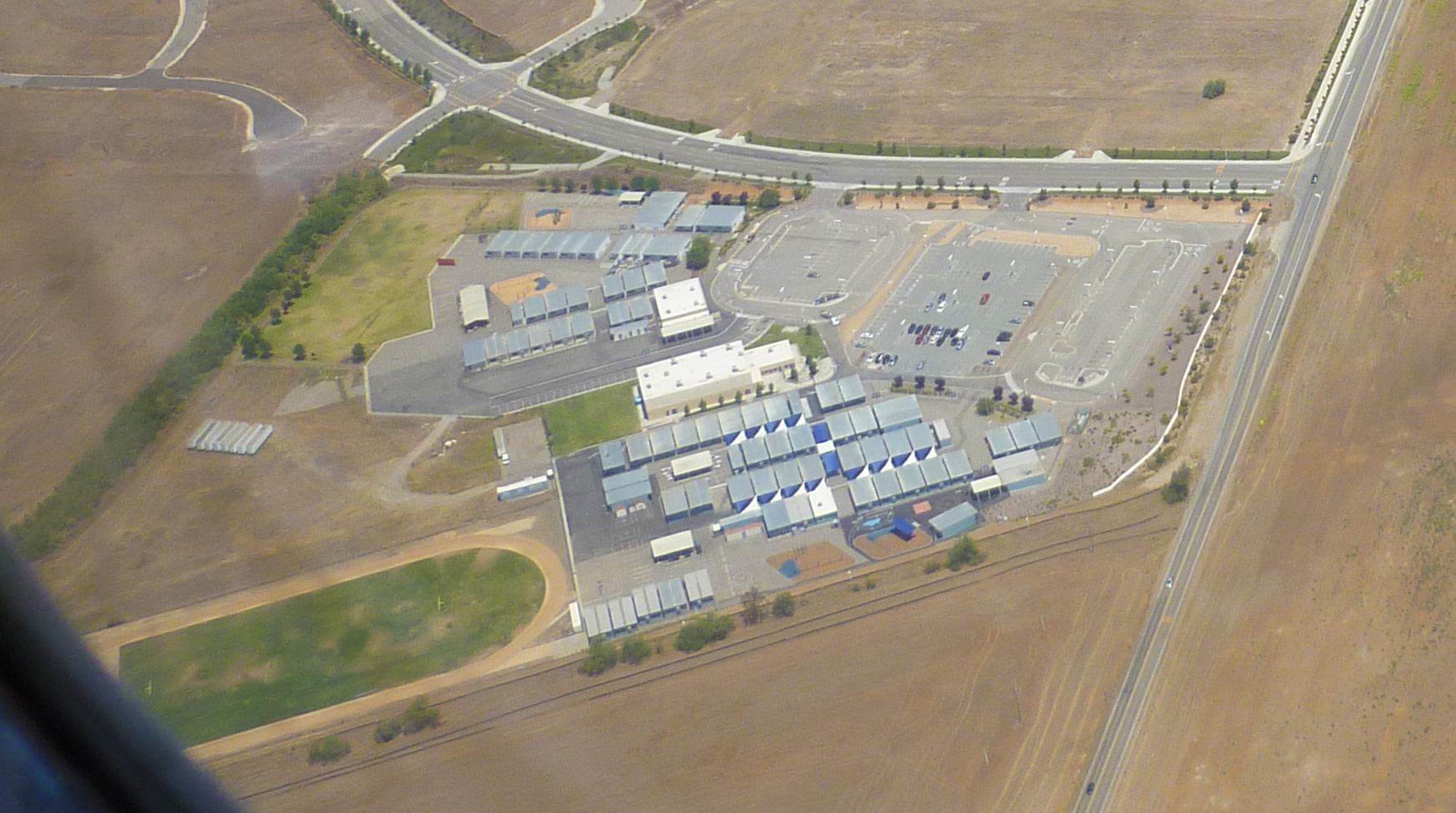 Aerial view of two school campuses surrounded by open land and parking lots.