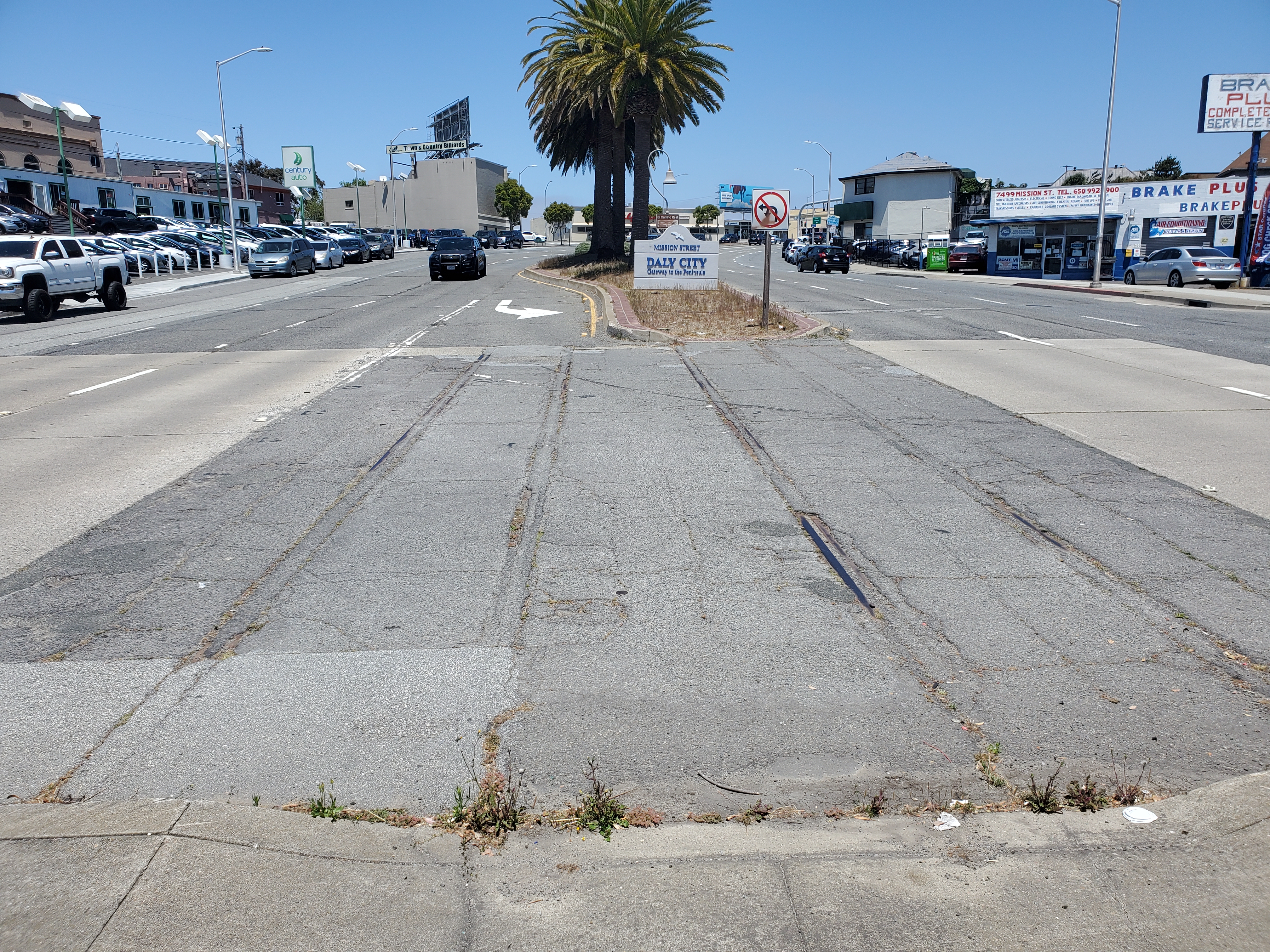 Wide multi-lane road with a concrete median and commercial buildings along the roadside.