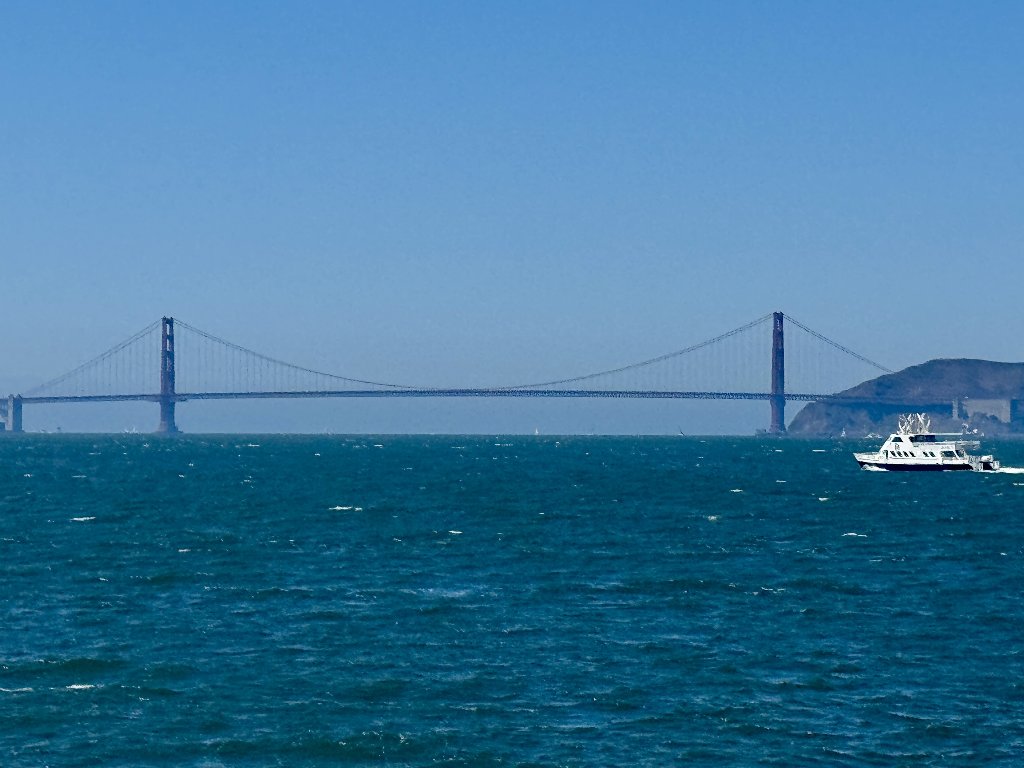 Golden Gate Bridge viewed from a passenger ferry crossing choppy San Francisco Bay.