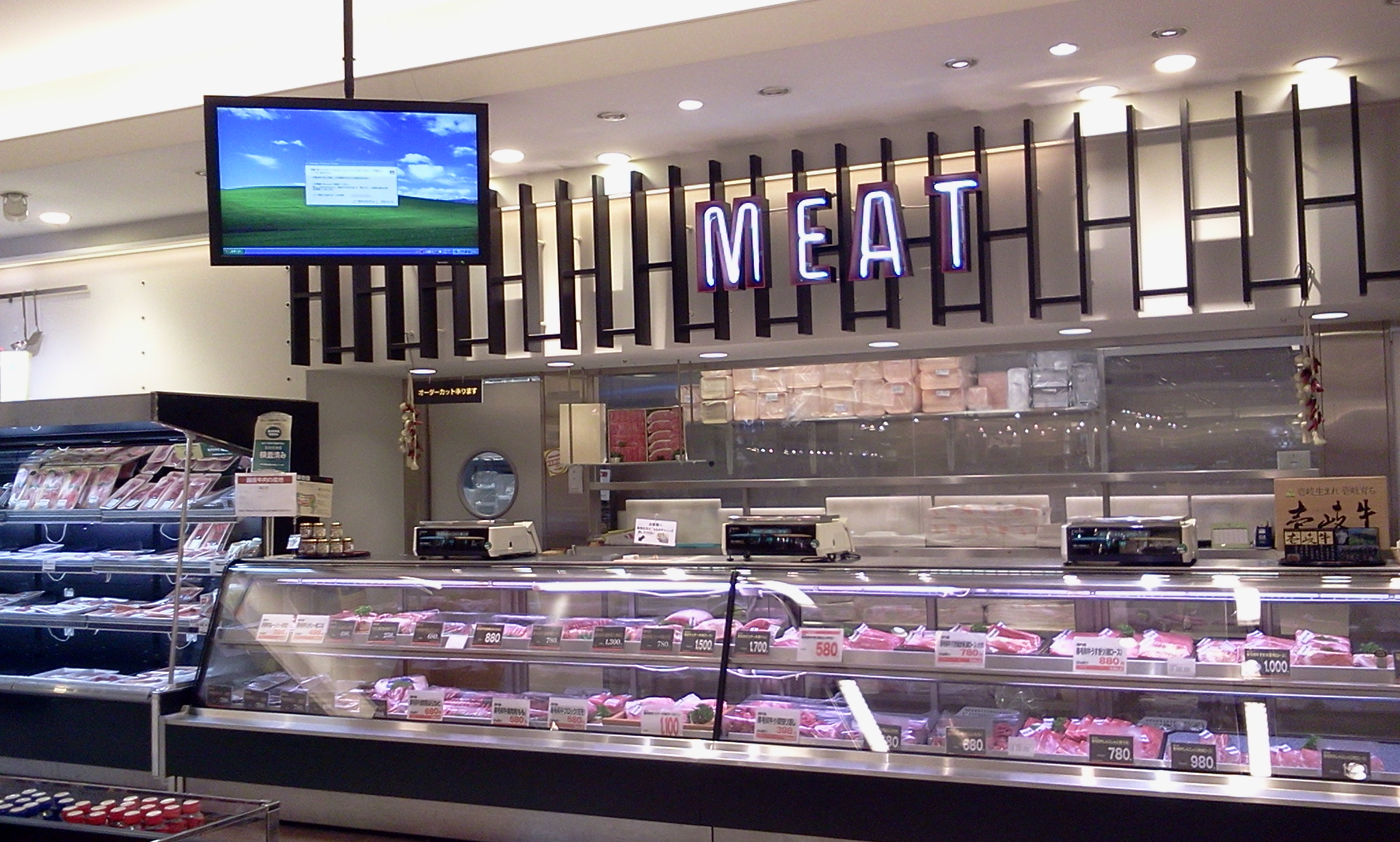 Refrigerated glass display cases filled with packaged meat at a grocery store butcher counter.