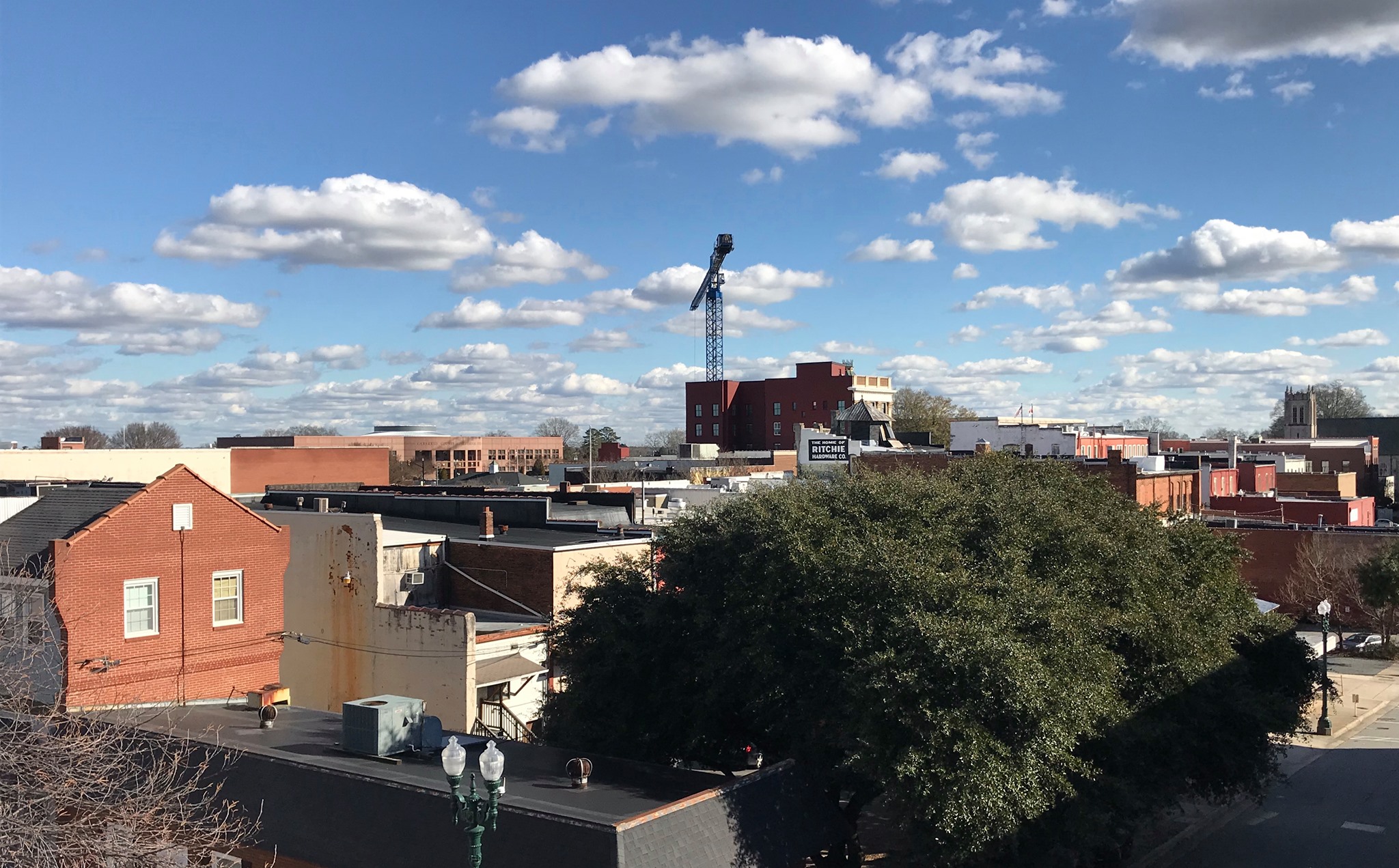 Elevated view of downtown Concord showing brick buildings, a construction crane, and a partly cloudy sky.