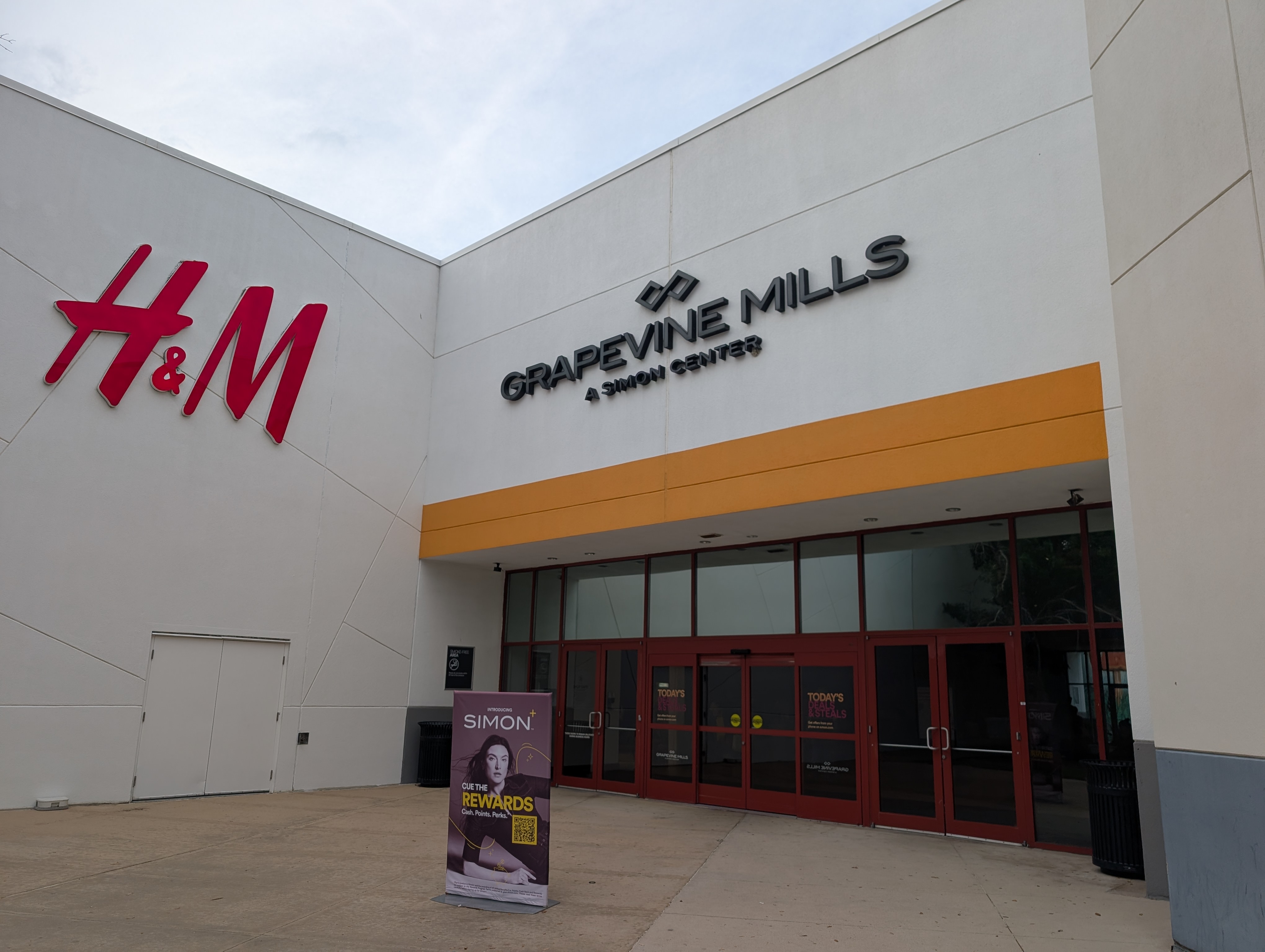 Mall entrance with Grapevine Mills name sign above red glass doors.