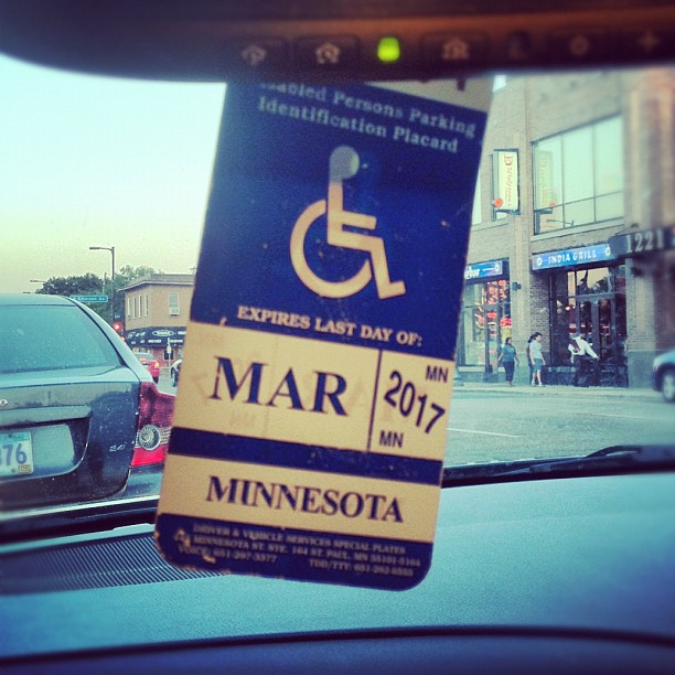 A blue disabled parking placard hanging from a vehicle's rearview mirror.