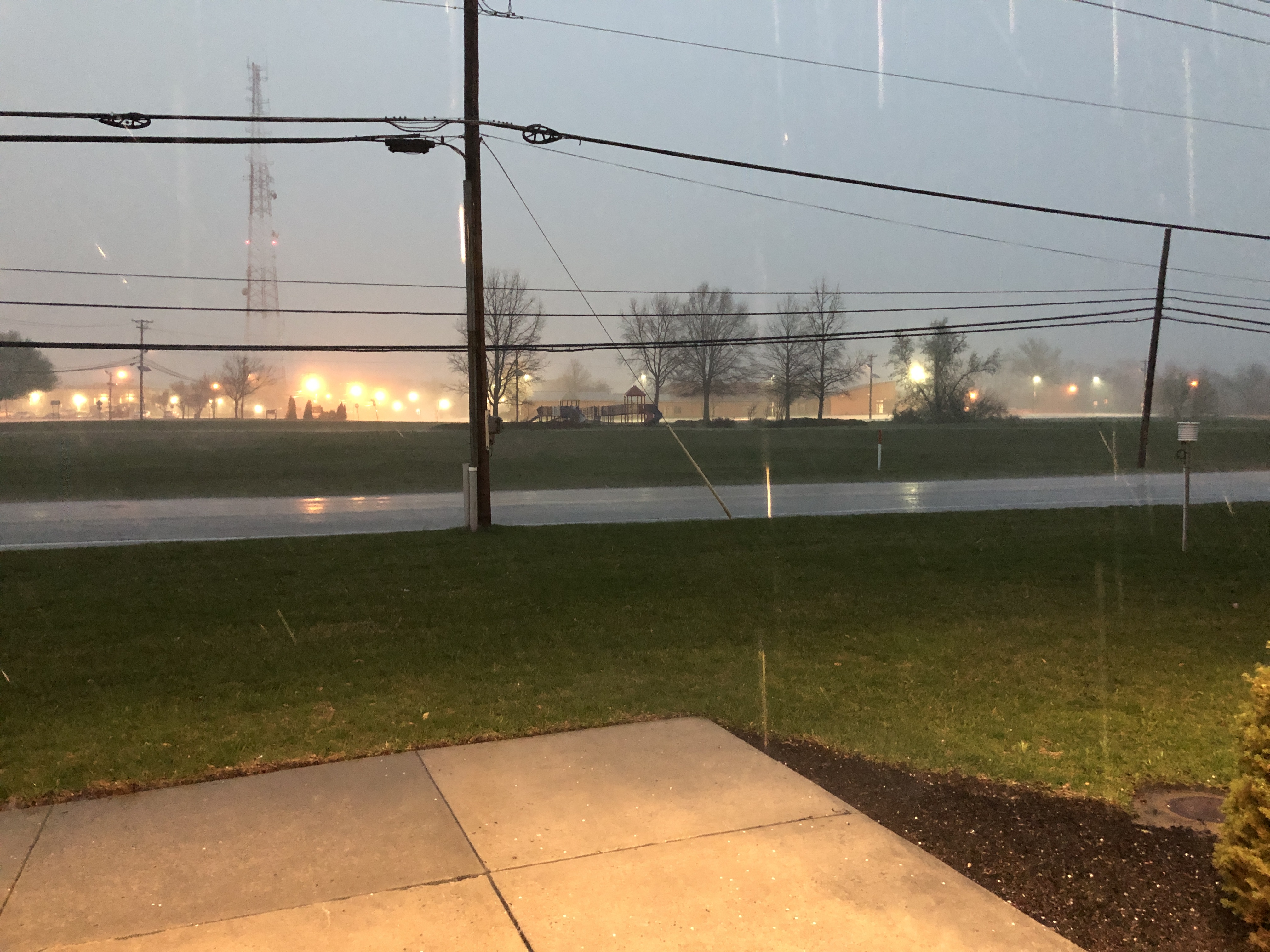 Heavy rain falls on a wet road with utility poles visible in the background.