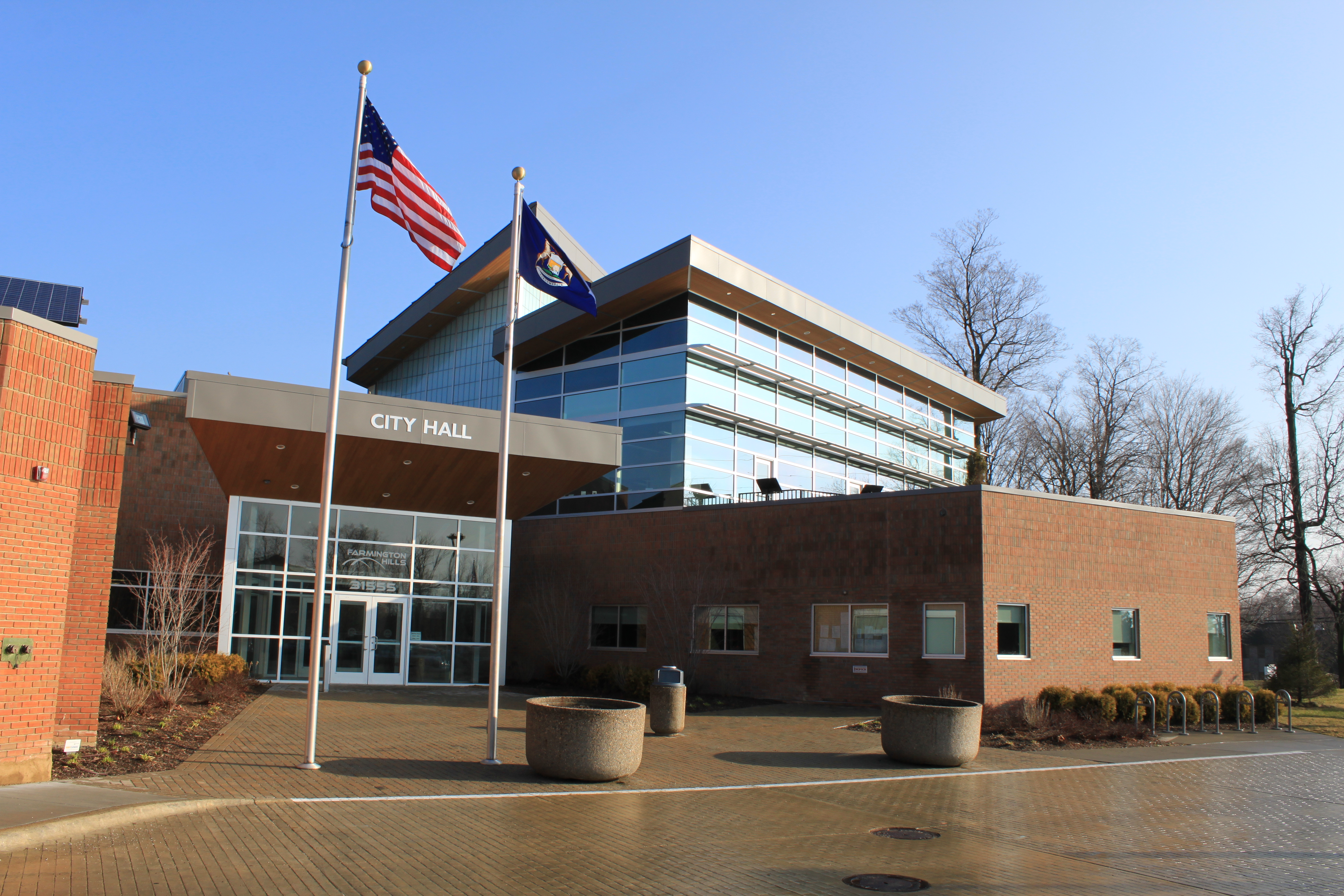 Modern brick and glass city hall building with two flagpoles out front.