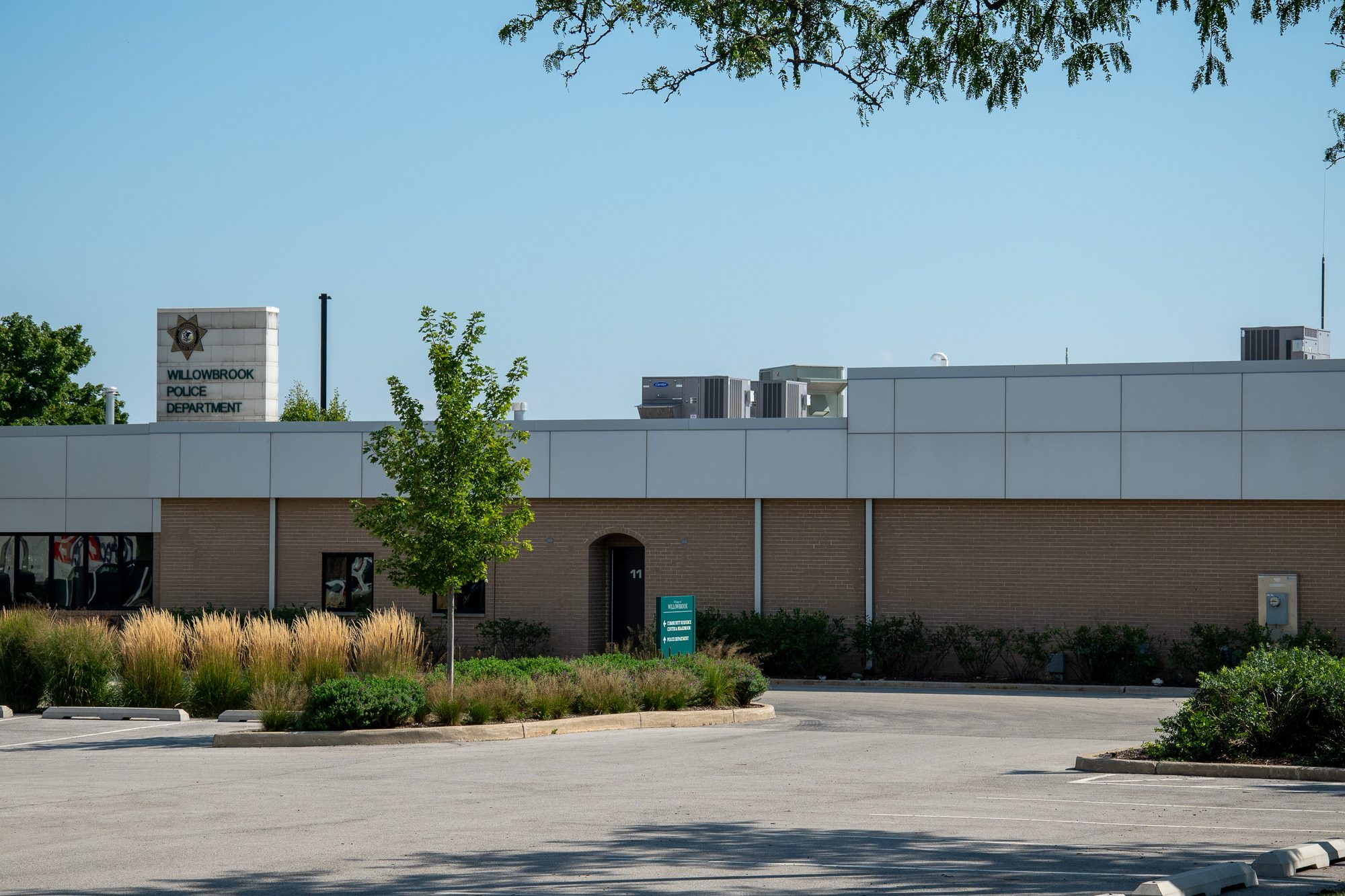 Single-story brick police station exterior with parking lot and landscaping.
