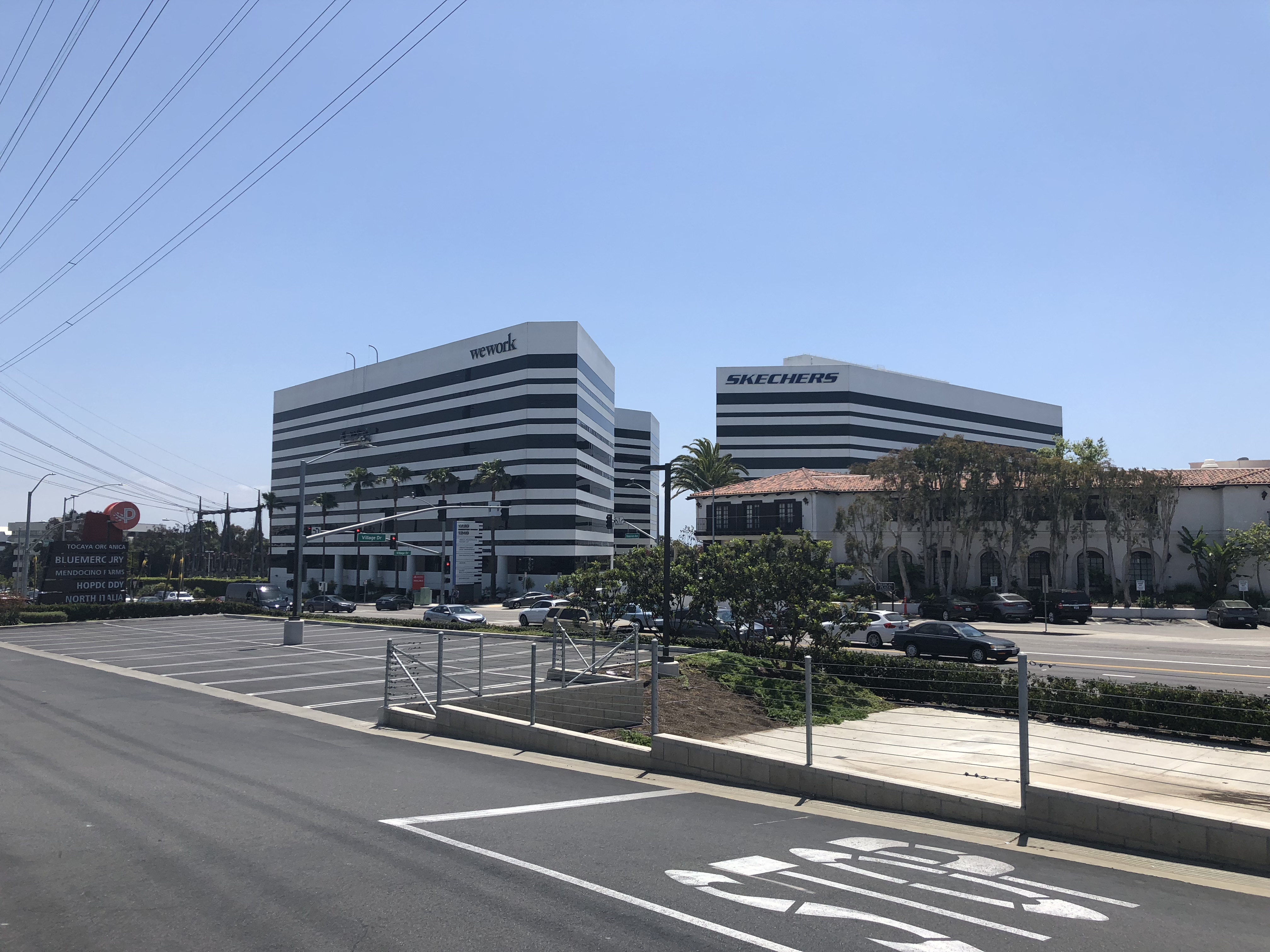 Two large striped office buildings along a wide road with palm trees in Redondo Beach.