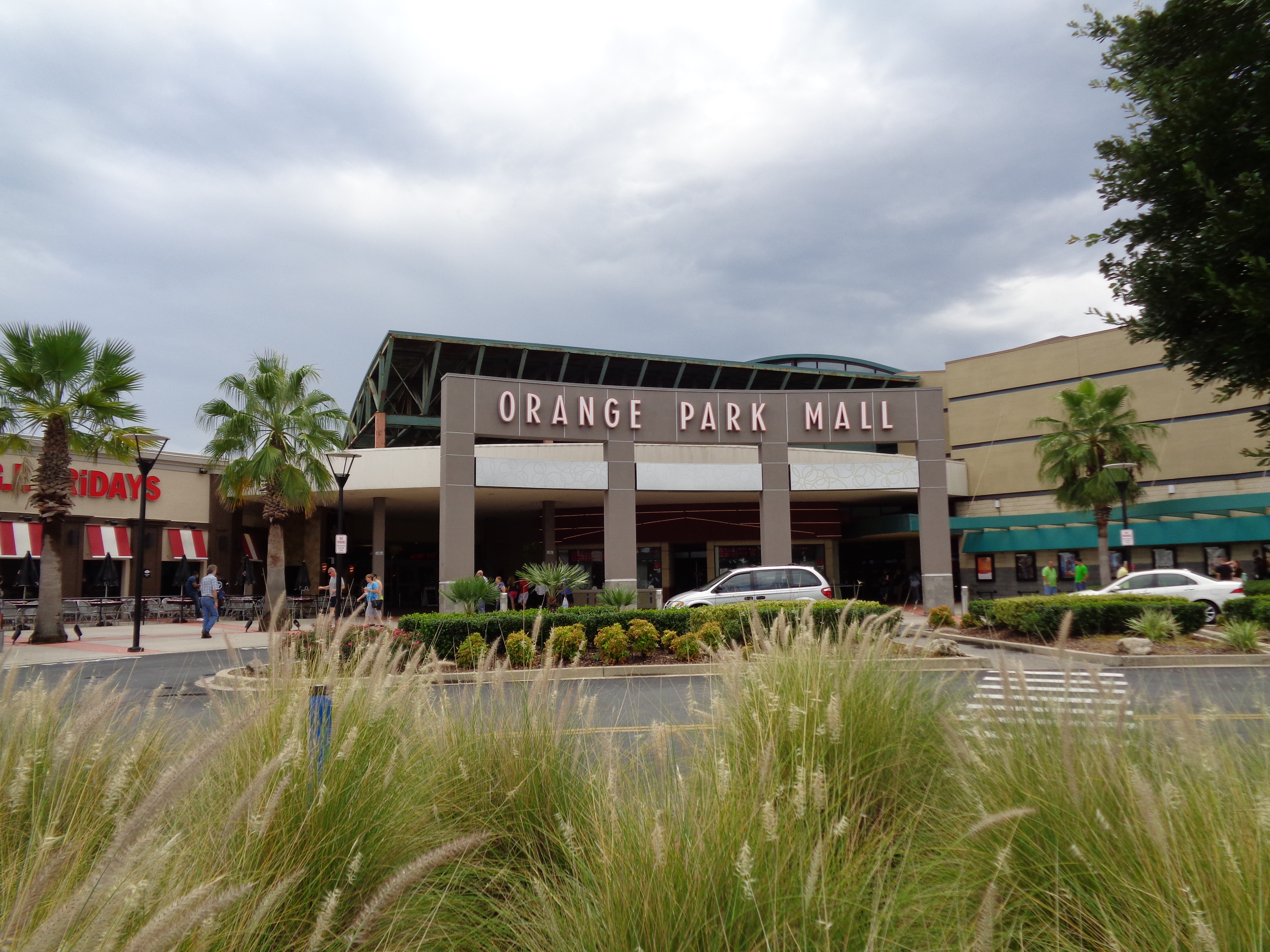 Exterior of Orange Park Mall with palm trees and parked cars out front.