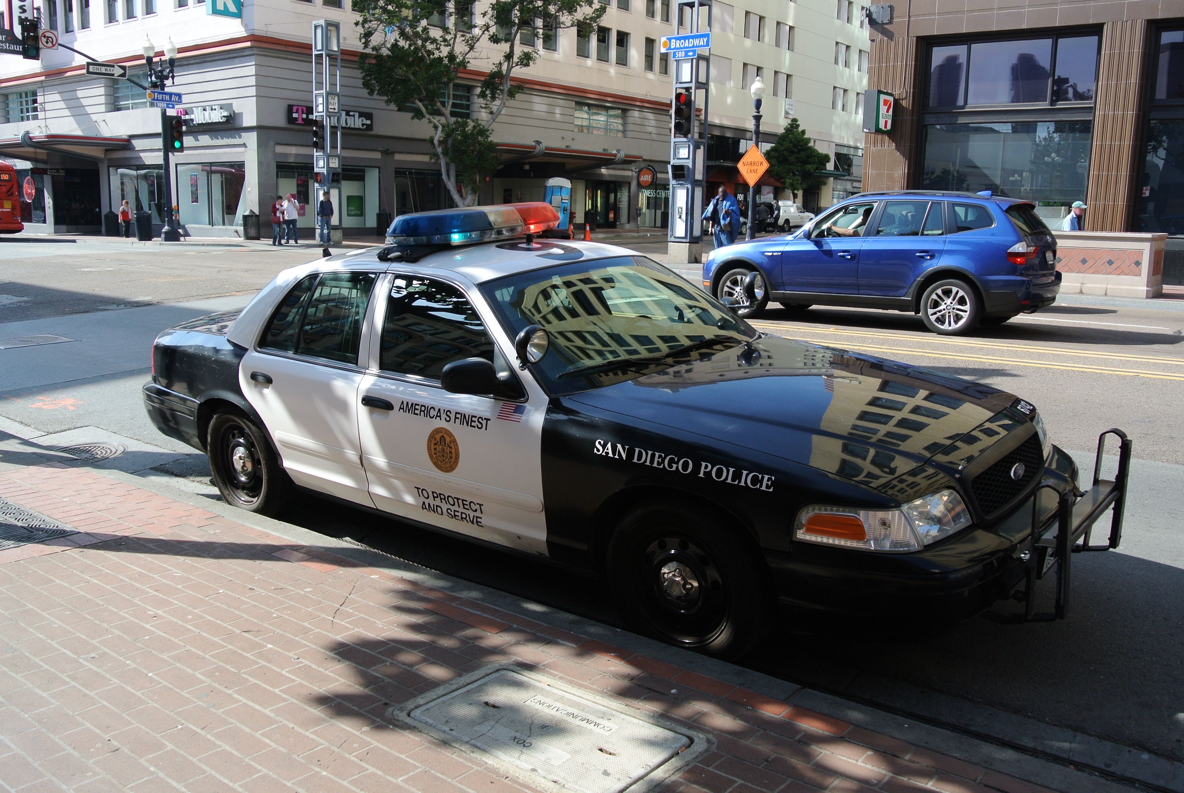 Black-and-white San Diego Police patrol car parked at a downtown street corner.