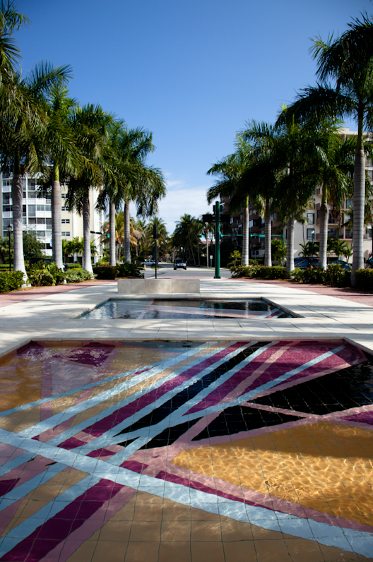 Palm-lined reflecting pool with colorful mosaic tiles at a Florida community center.