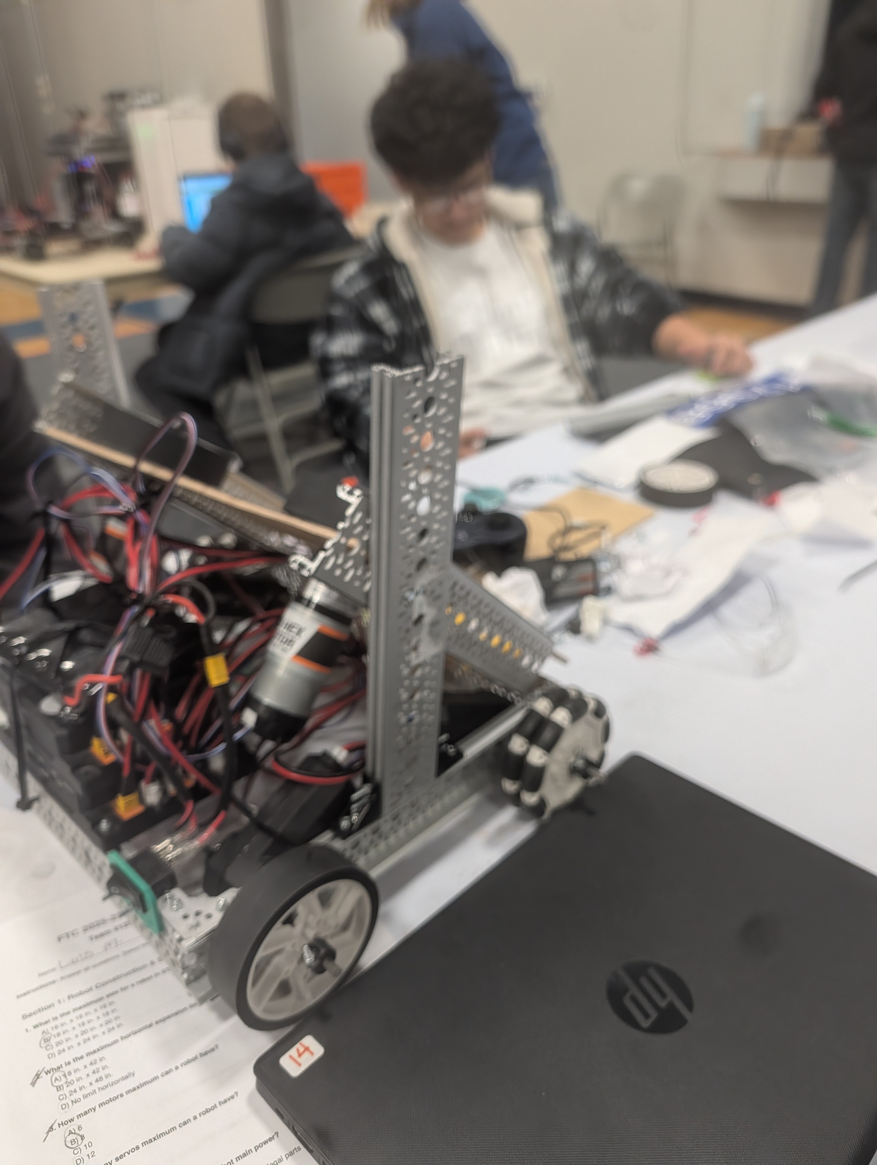 A VEX robotics robot with metal frame and wheels on a classroom workbench.