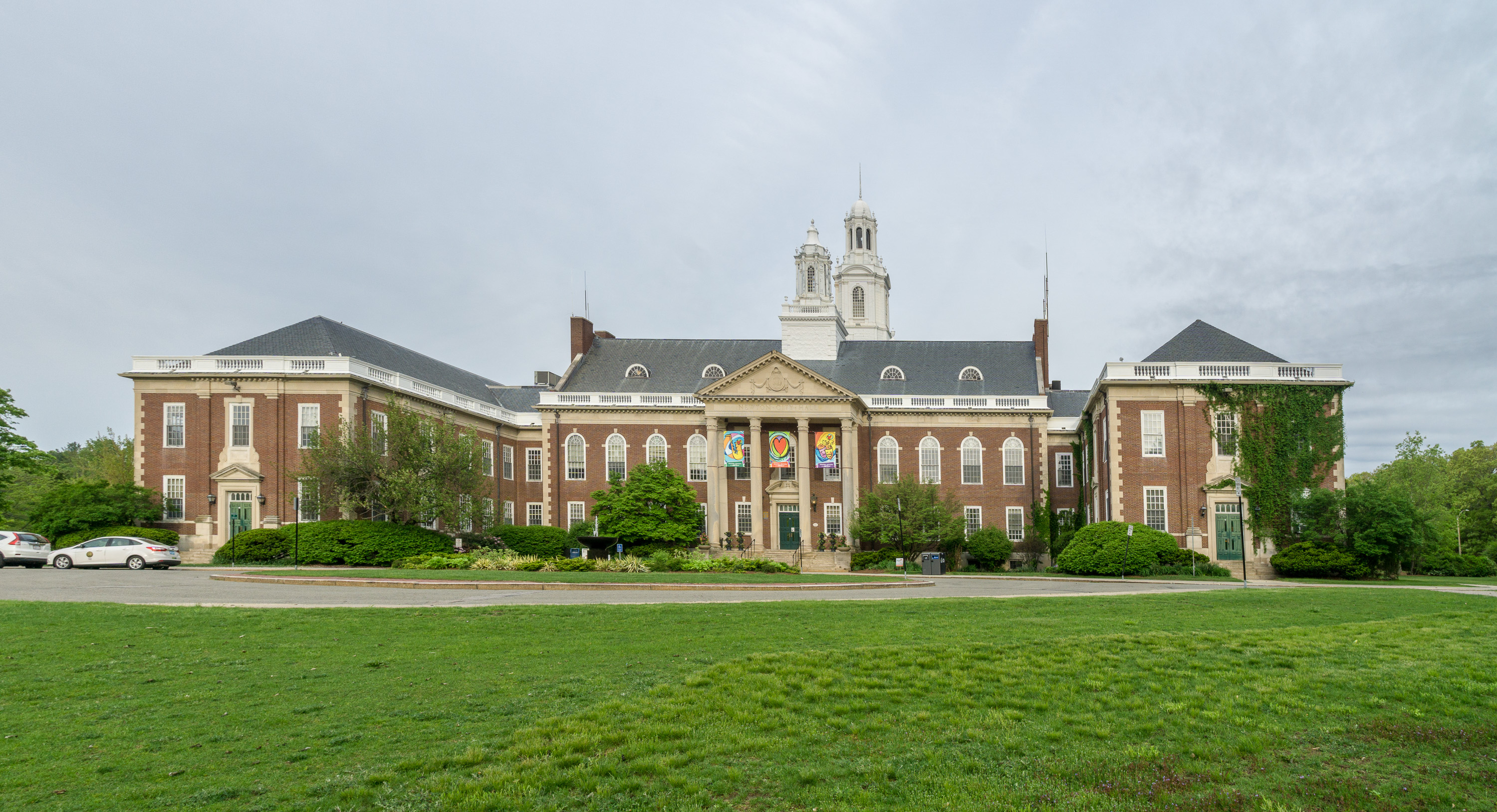 Wide view of a large red-brick municipal building with a white cupola and green lawn in front.
