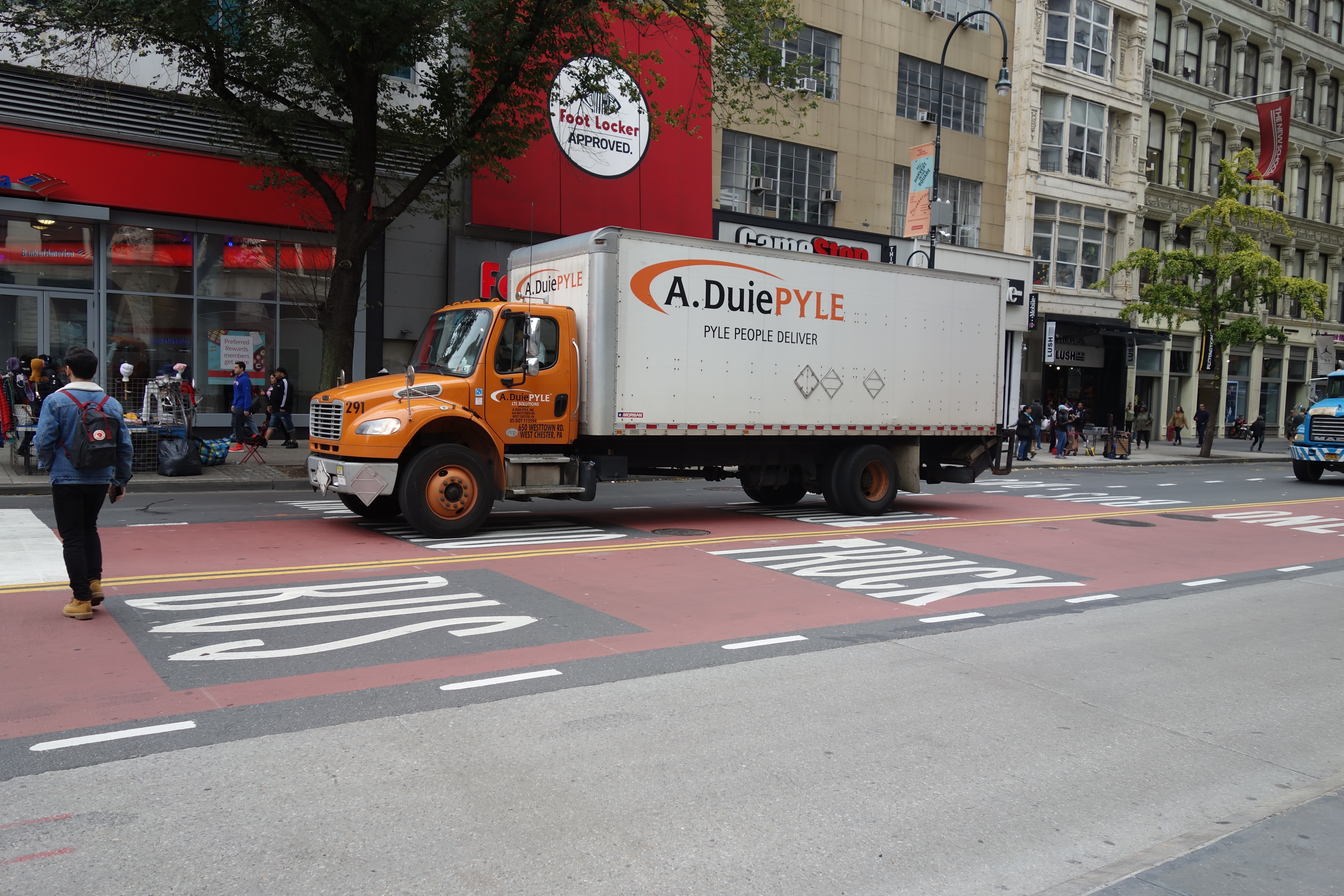 Orange A. Duie Pyle box truck stopped at a city traffic light.