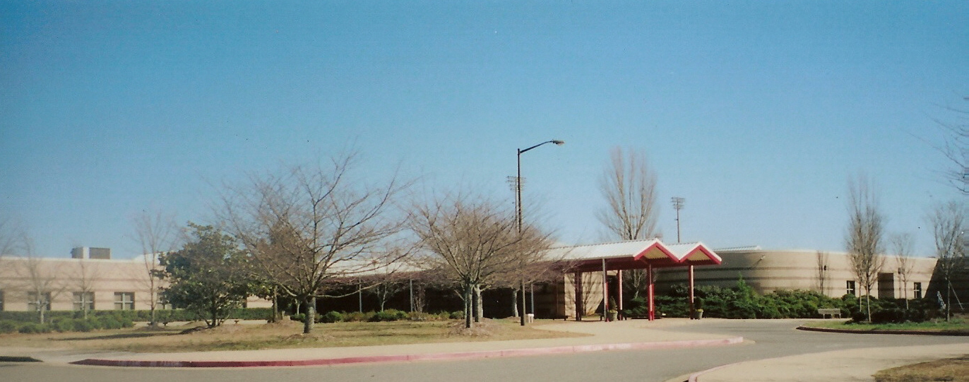 Exterior of a school building with a covered drop-off area and large windows.