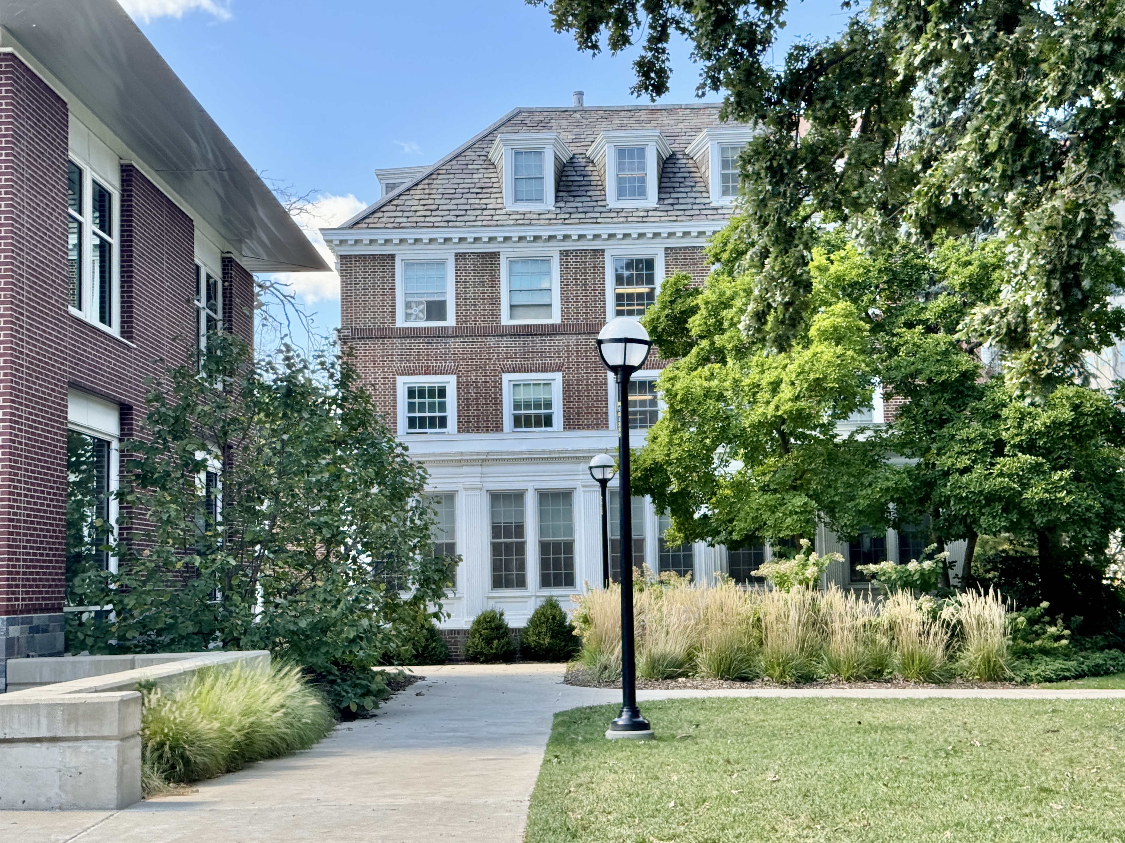 Brick Colonial Revival dormitory surrounded by trees and landscaping on a university campus.