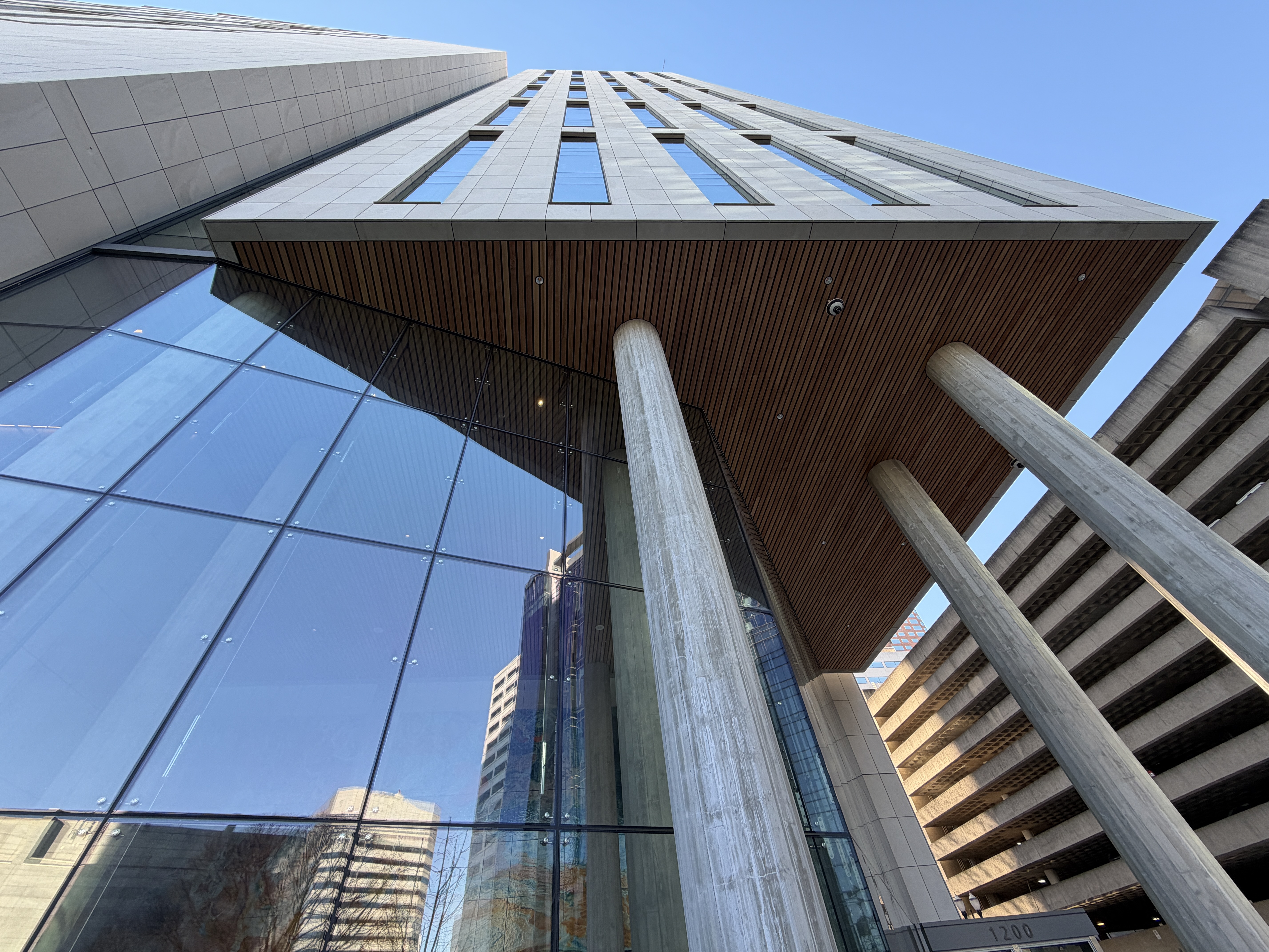 Low-angle view of a modern courthouse building with concrete columns and a glass facade.