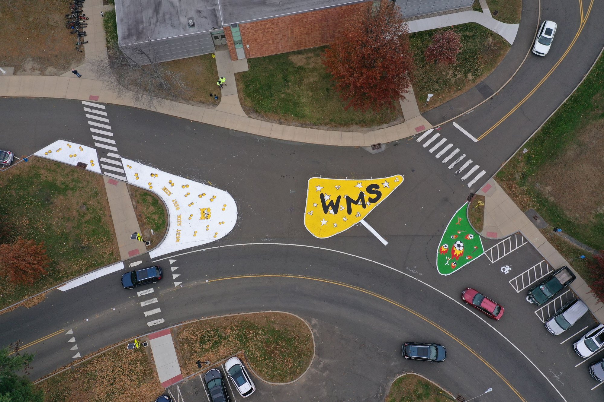 Aerial view of an intersection with colorful painted temporary traffic safety markings near a school.