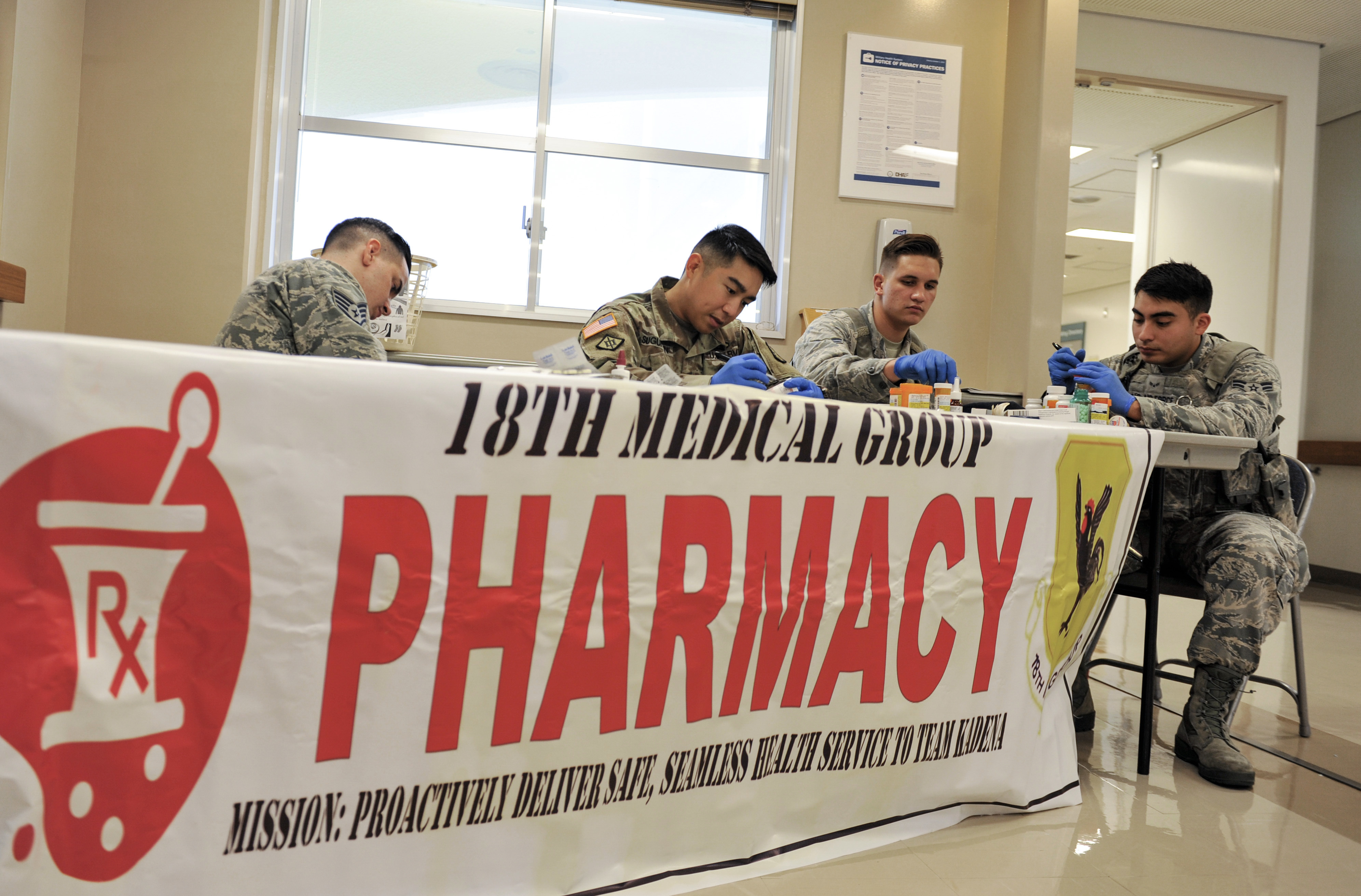 Four uniformed workers sort collected medications on a table at a drug take-back event.