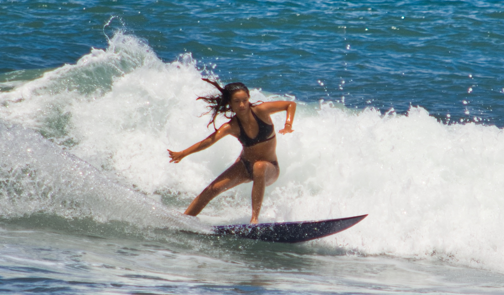 A surfer rides a breaking ocean wave on a surfboard.