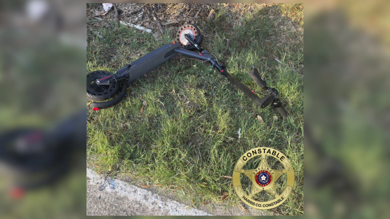 Electric scooter lying on green grass.