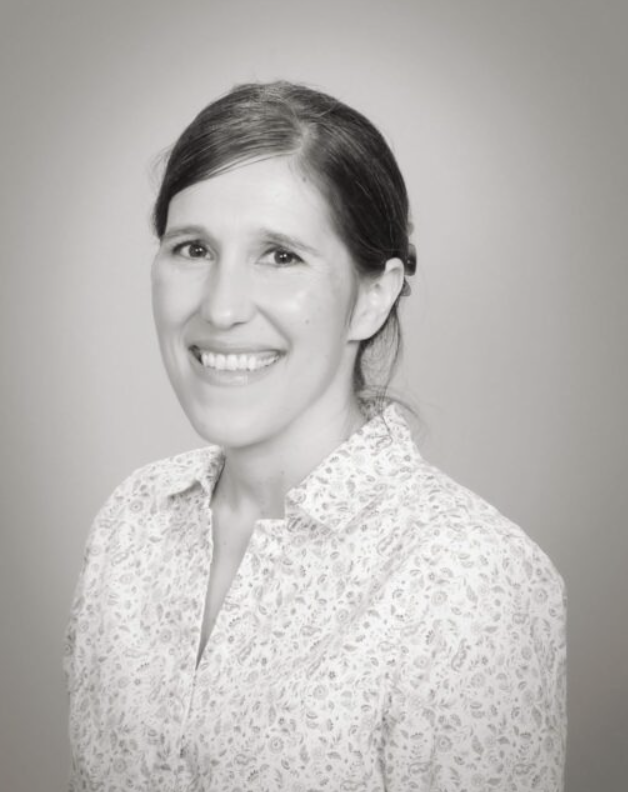Black-and-white portrait of Sibyl Minighini smiling in a patterned blouse.
