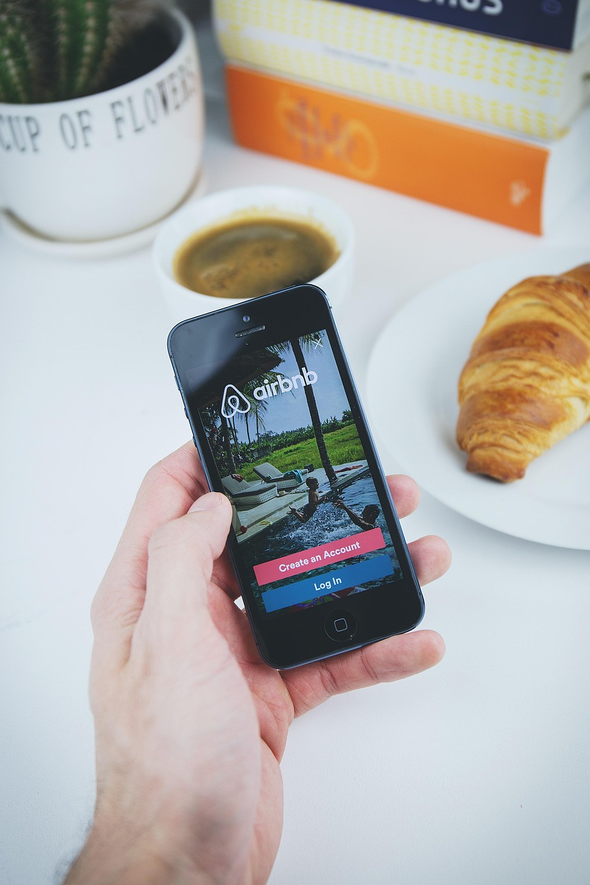 Airbnb, app, apple, book, coffee, croissant, hand, holding, ios, iphone, mobile, phone, table, white, airbnb, airbnb, ai