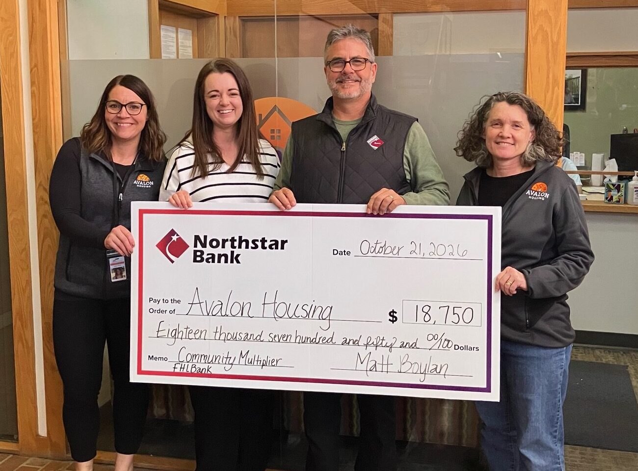 Four people holding a large ceremonial check for $18,750 from a bank to a housing nonprofit.