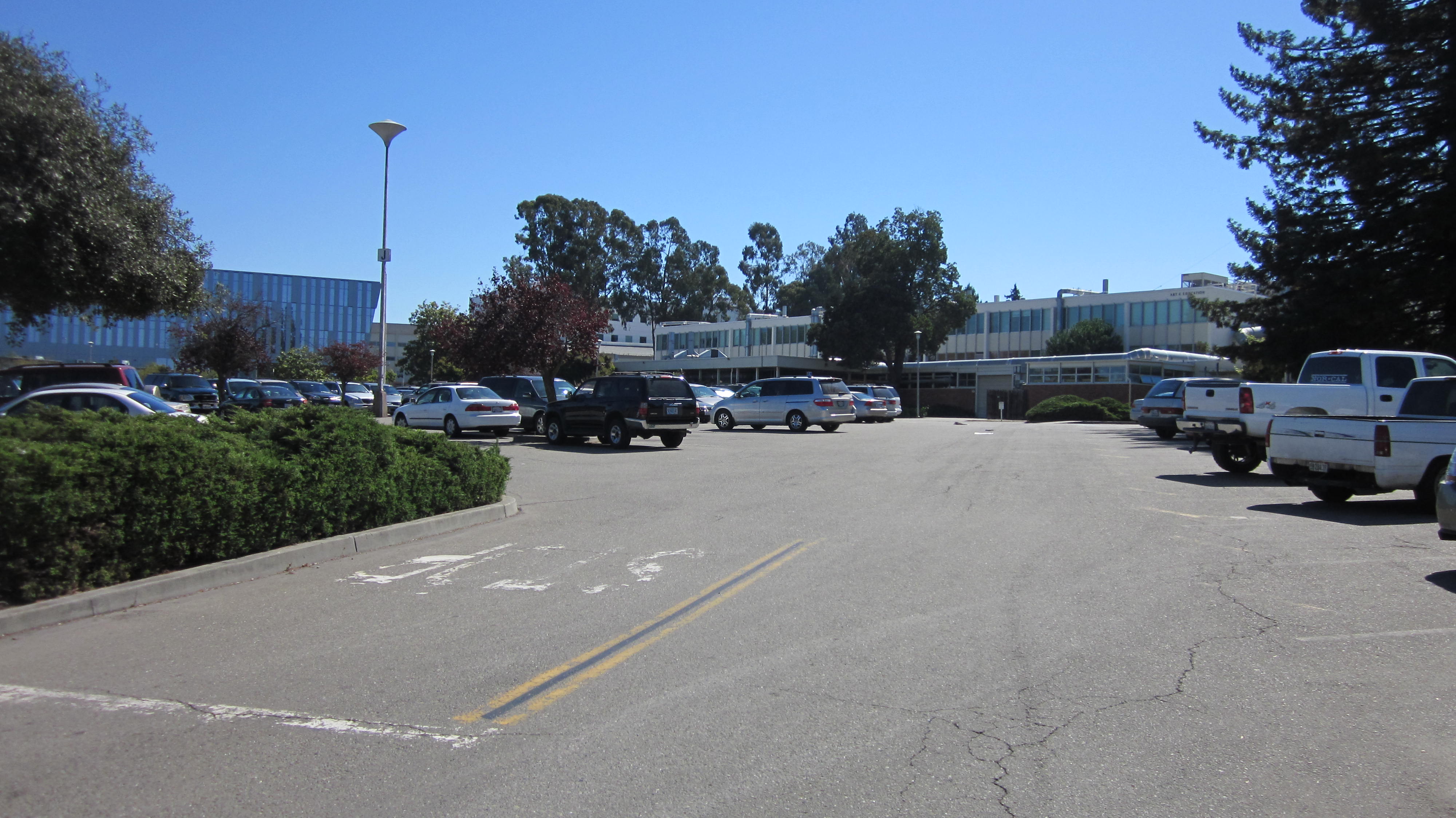 Low-rise campus buildings and a parking lot at a California state university under blue sky.