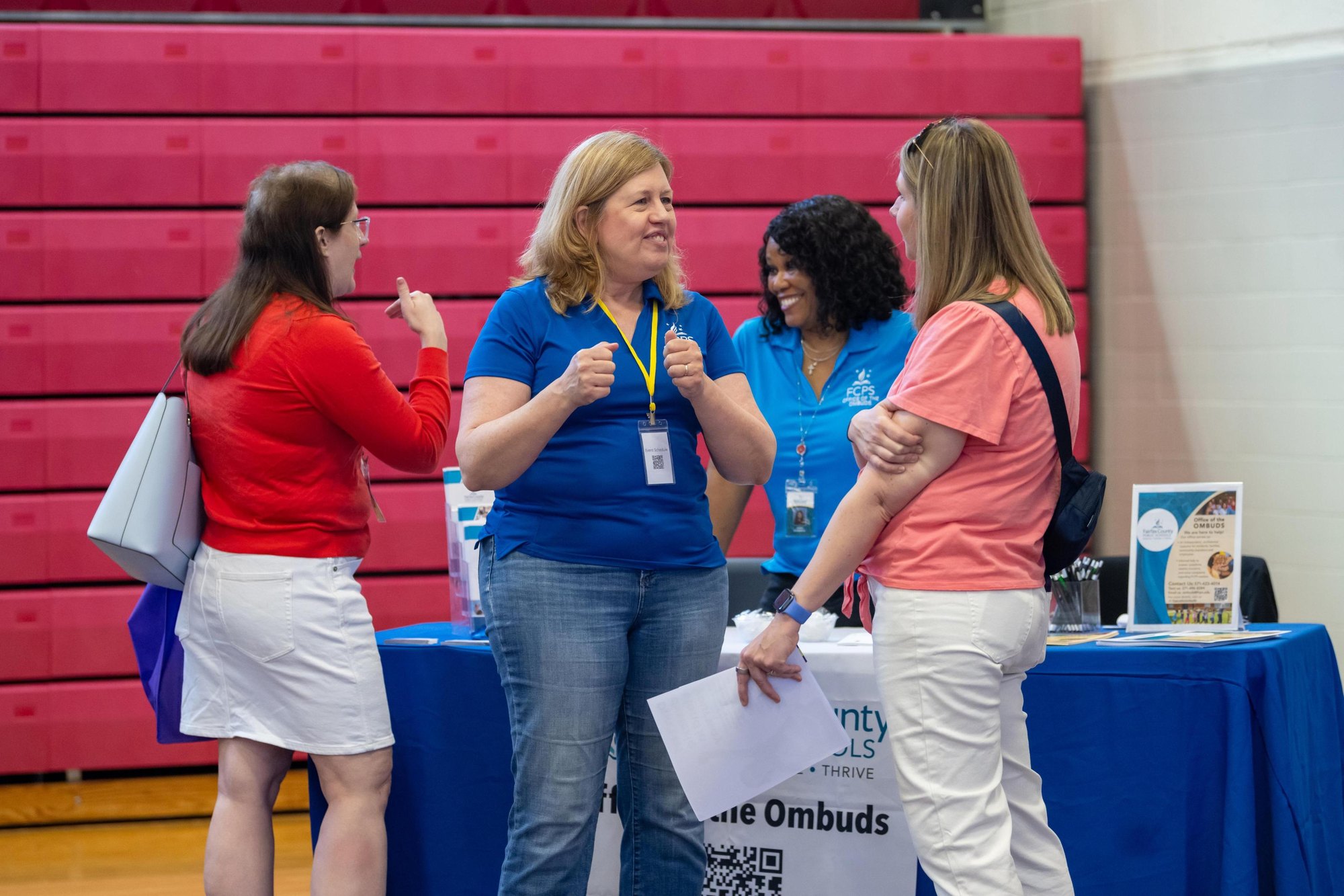 Four women talking at an information fair table with an Ombuds banner.