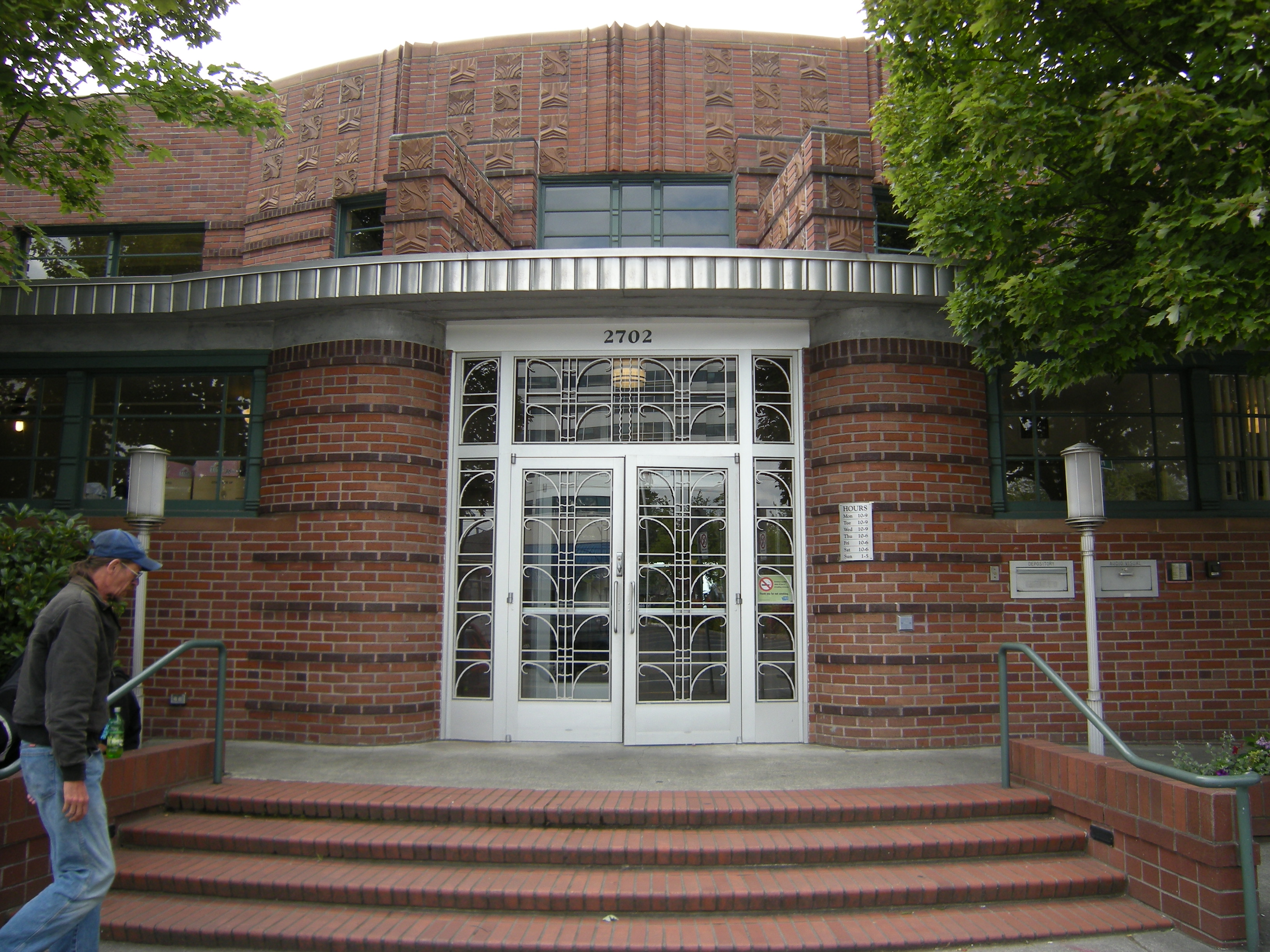 Red-brick Art Deco library entrance with ornate glass double doors and brick steps.