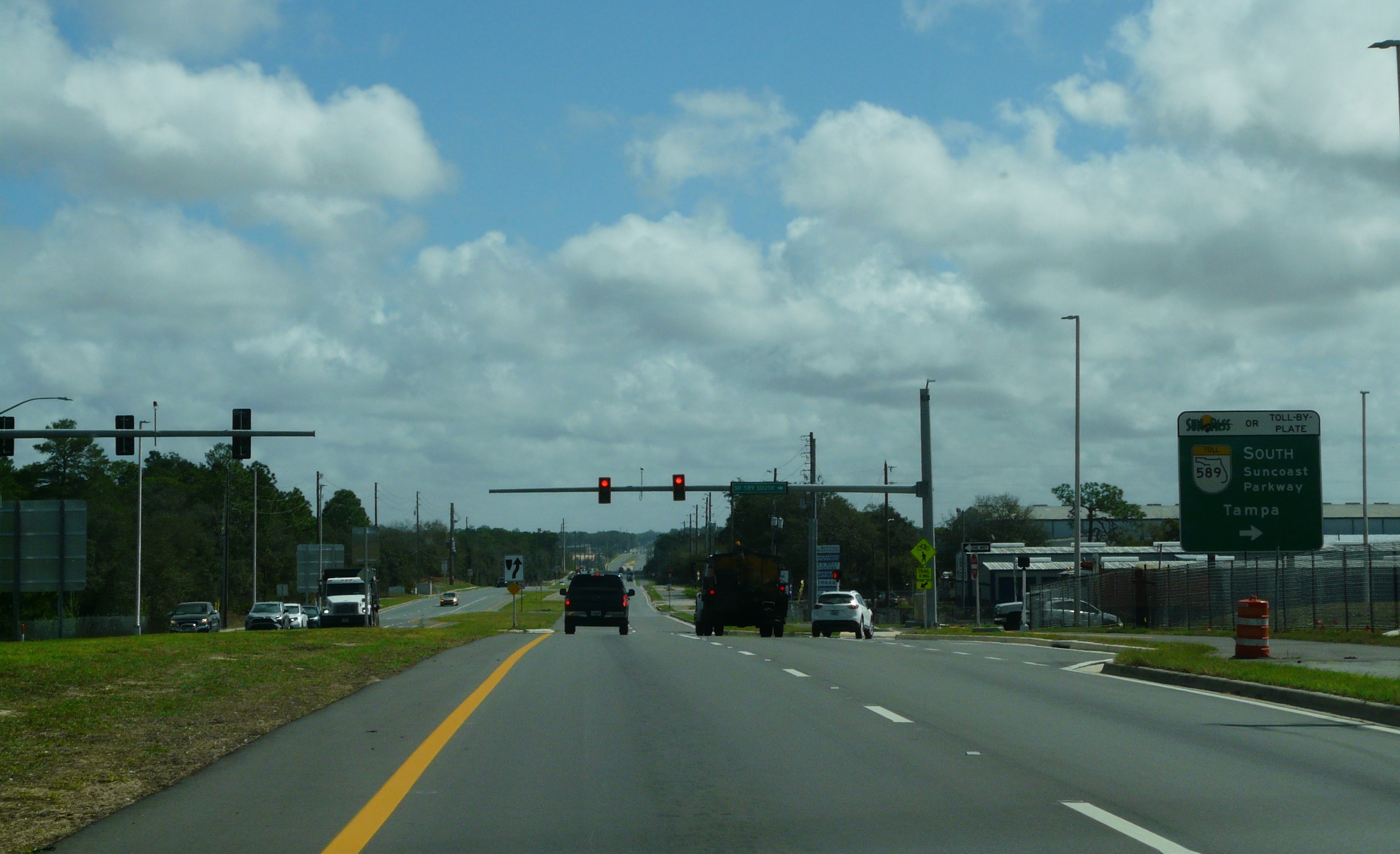 Multi-lane highway with green overhead sign directing drivers to Suncoast Parkway southbound.