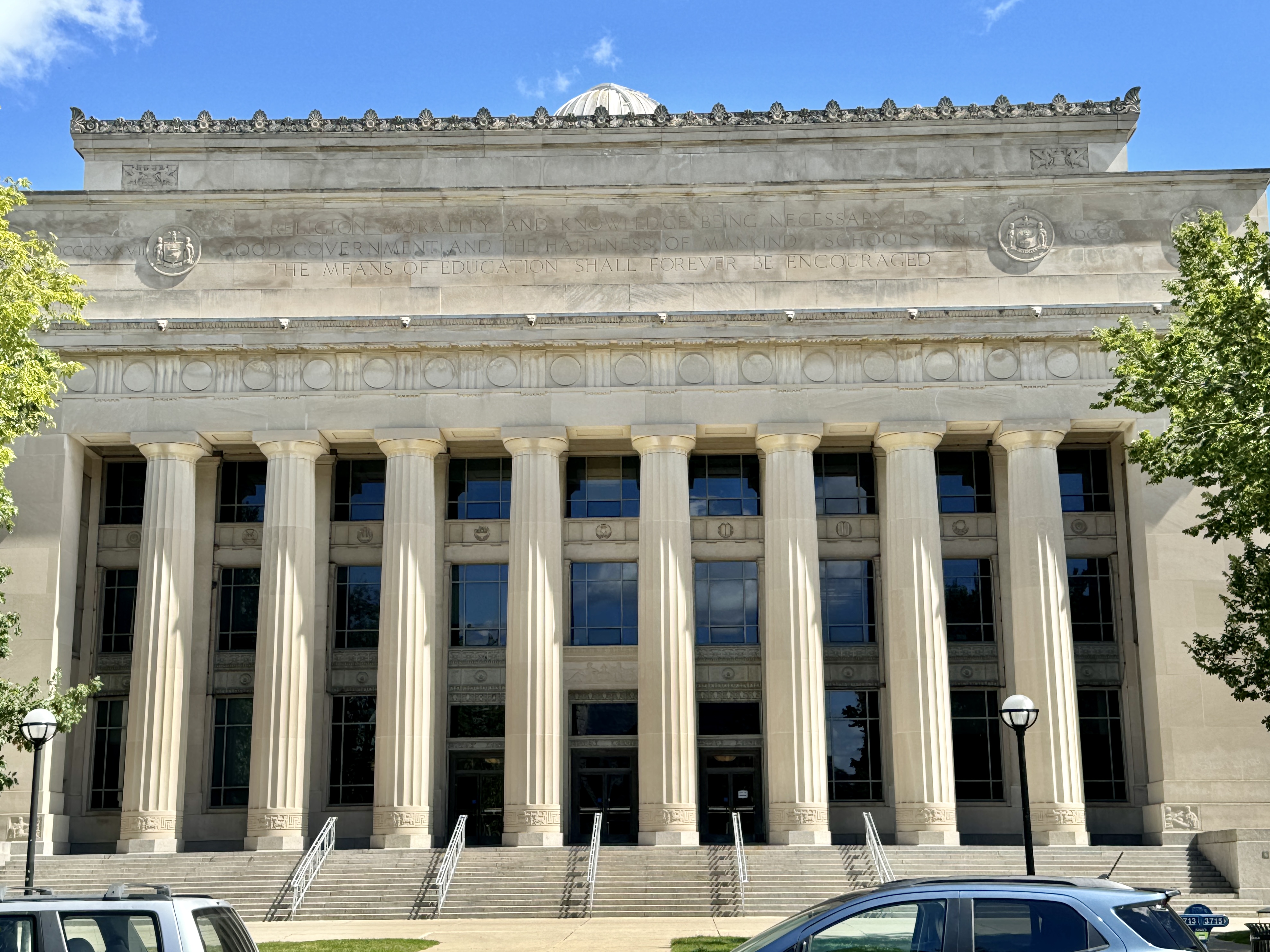 Classical Revival limestone building with tall Doric columns on a university campus.