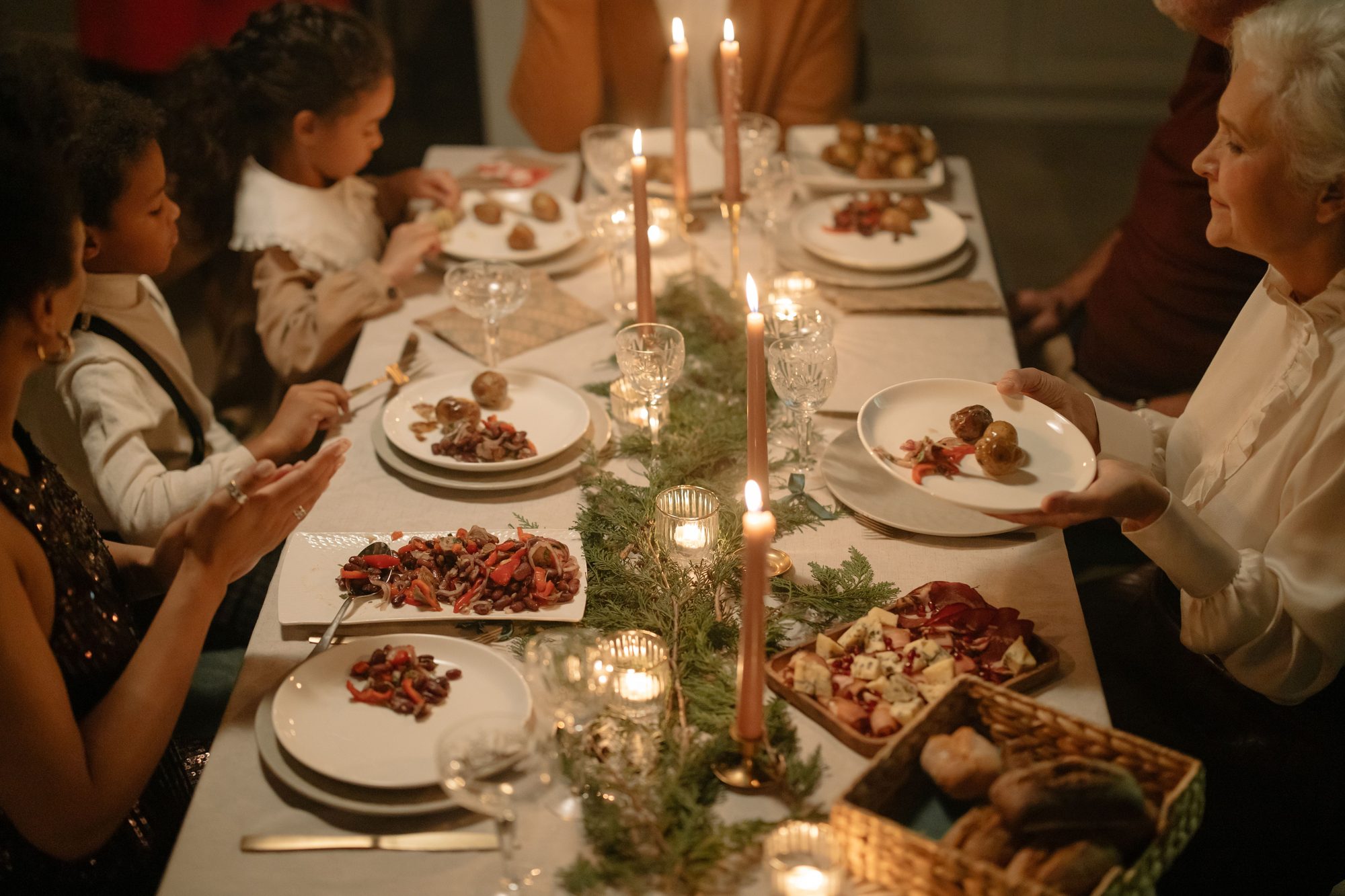 A diverse family enjoying a holiday dinner with candles and festive setting.