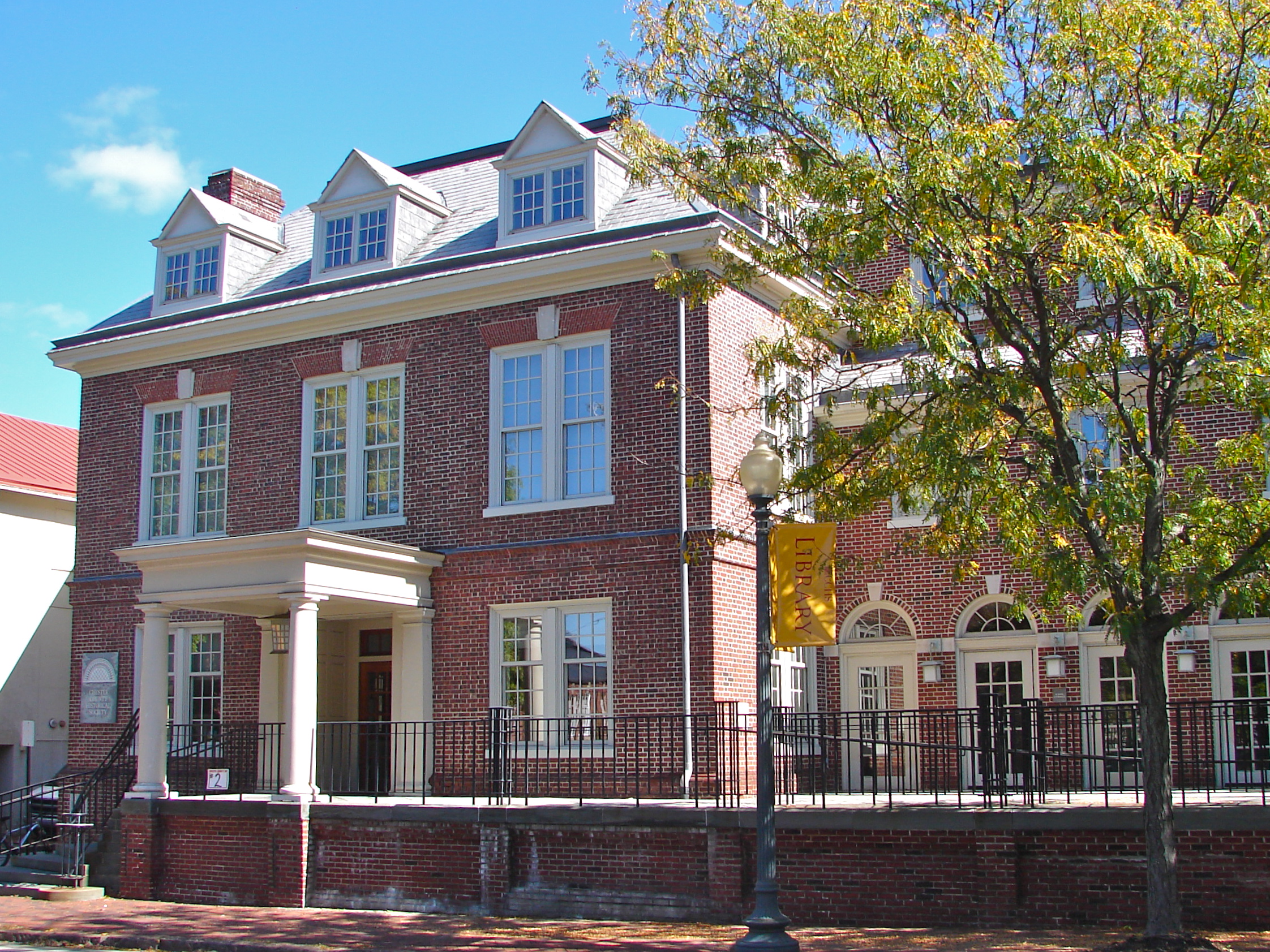 Red brick Georgian-style building with white trim, dormer windows, and columned entrance.