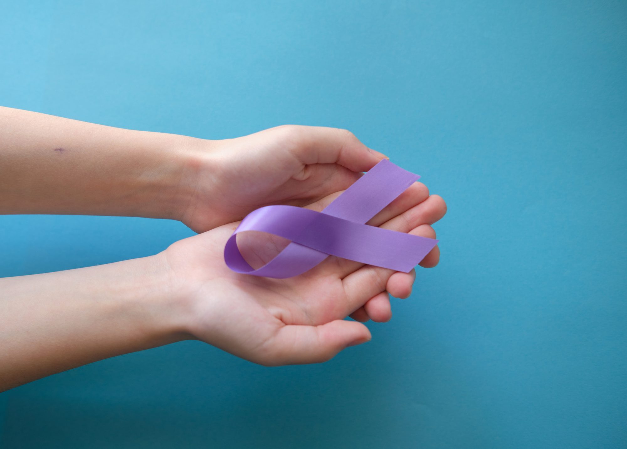Purple violet symbolic ribbon - the problem of pancreatic cancer, cystic fibrosis, fibromyalgia. Two crossed hands on a blue background