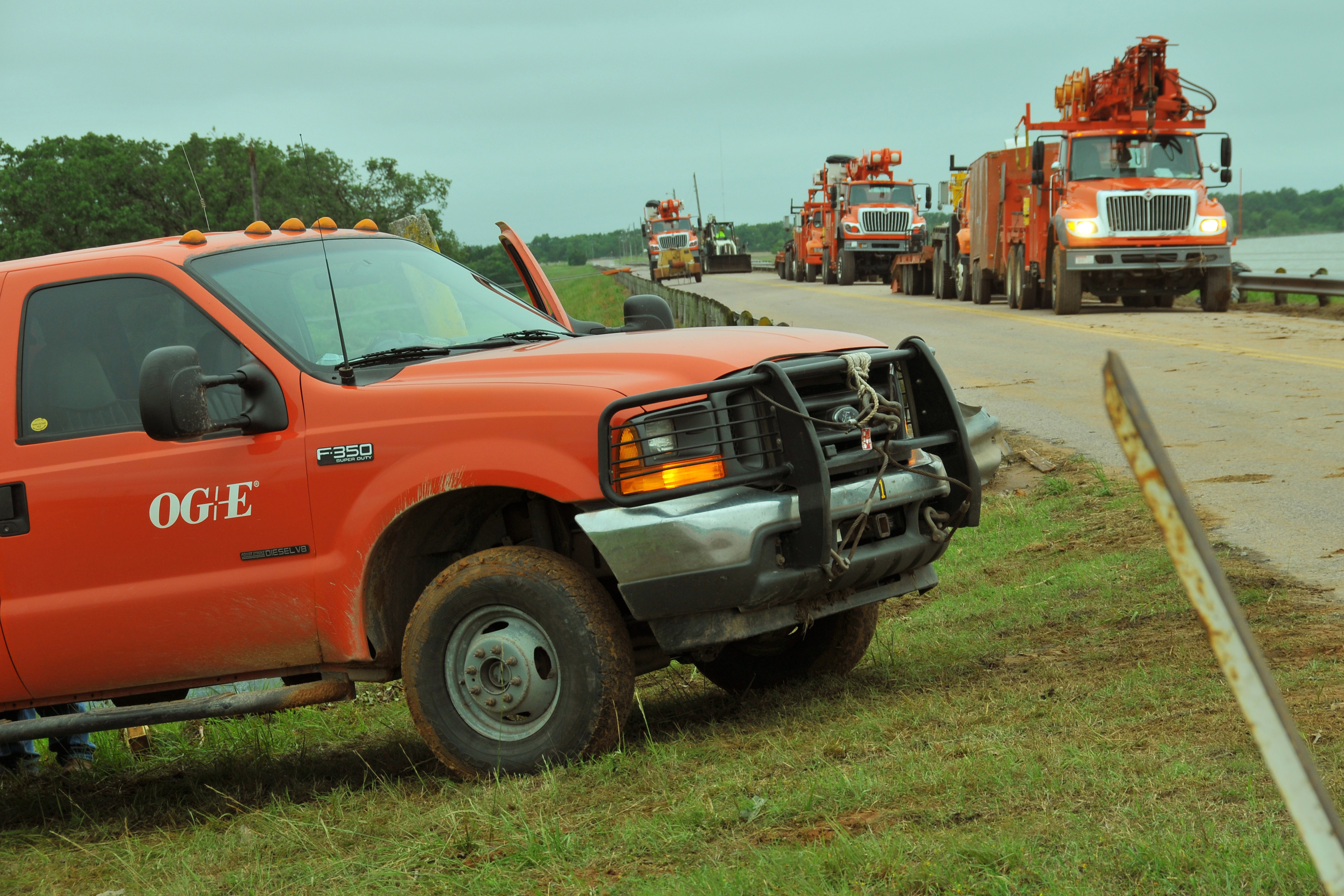 A convoy of utility trucks lined up along a road, ready for storm-damage repair.