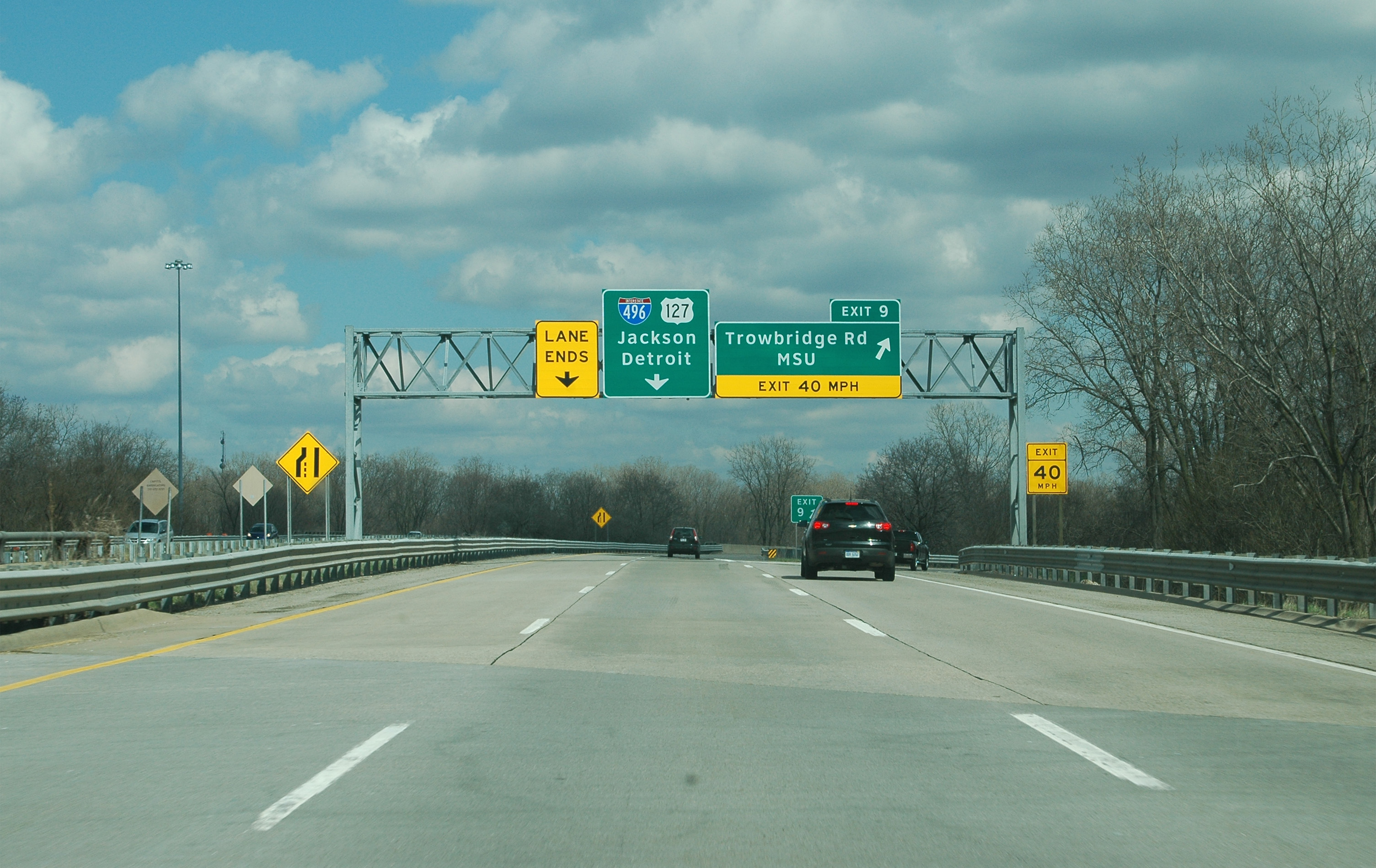 Multi-lane highway interchange with overhead green directional signs and light traffic.